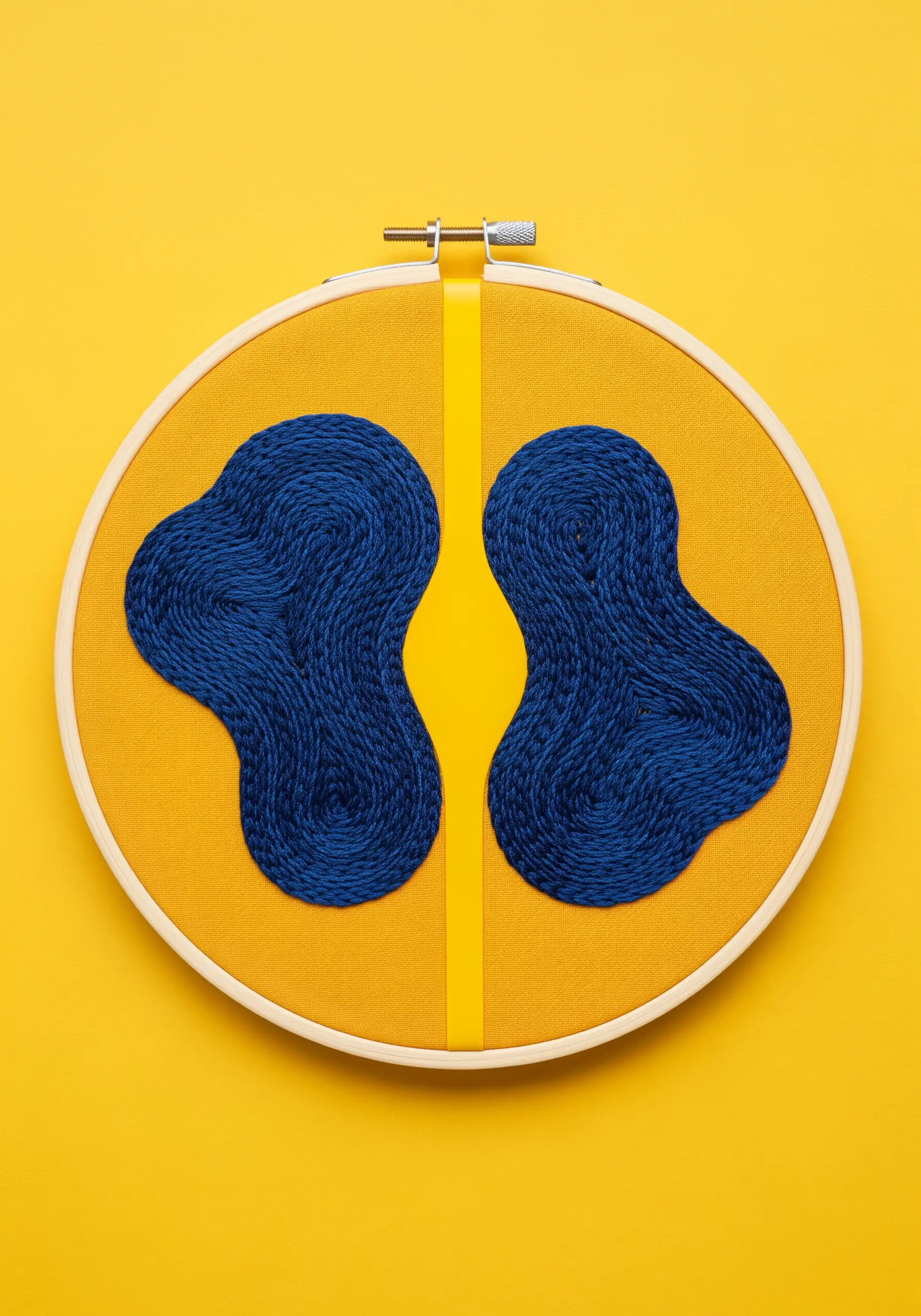 Two blue organic shapes separated by a vertical yellow ribbon on yellow fabric.