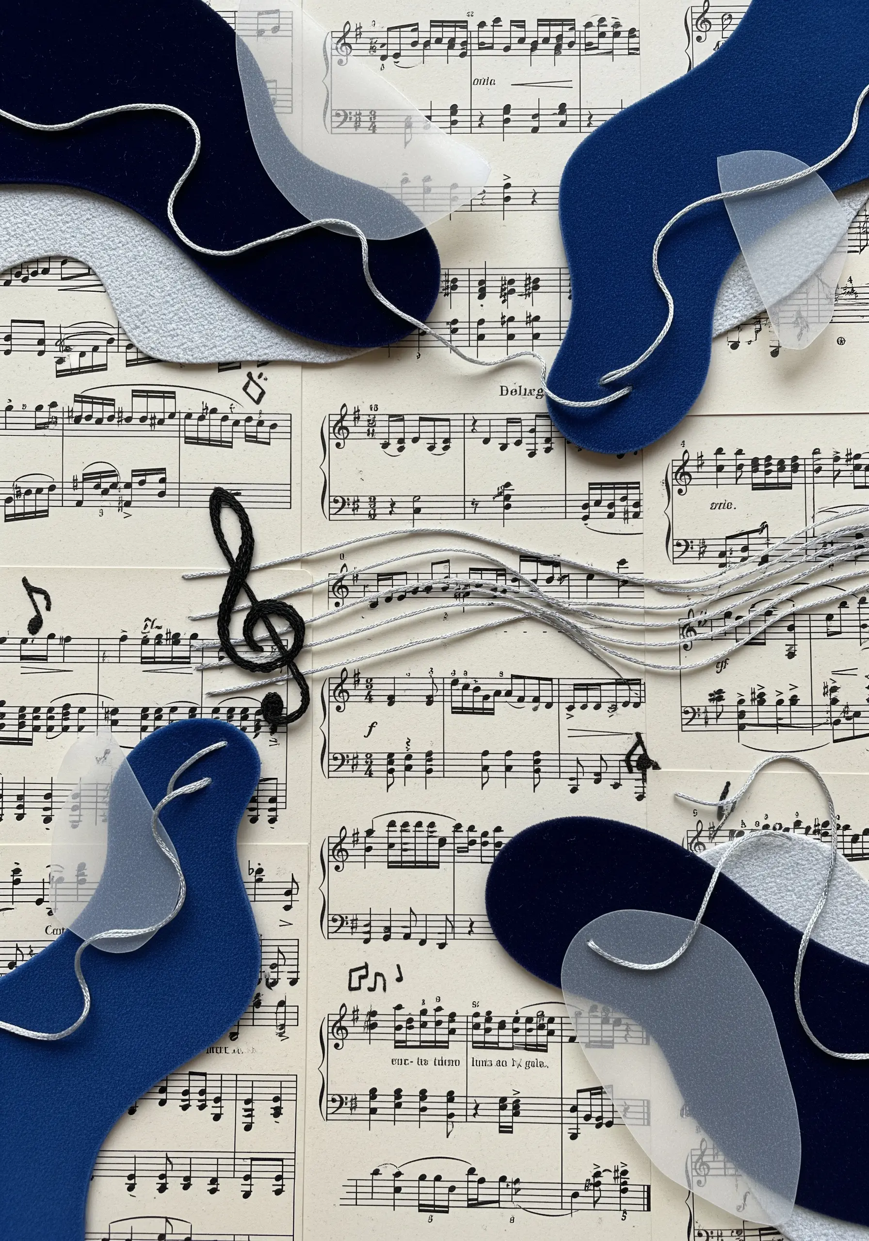 Abstract collage on sheet music with felt shapes and flowing lines of couched silver thread.