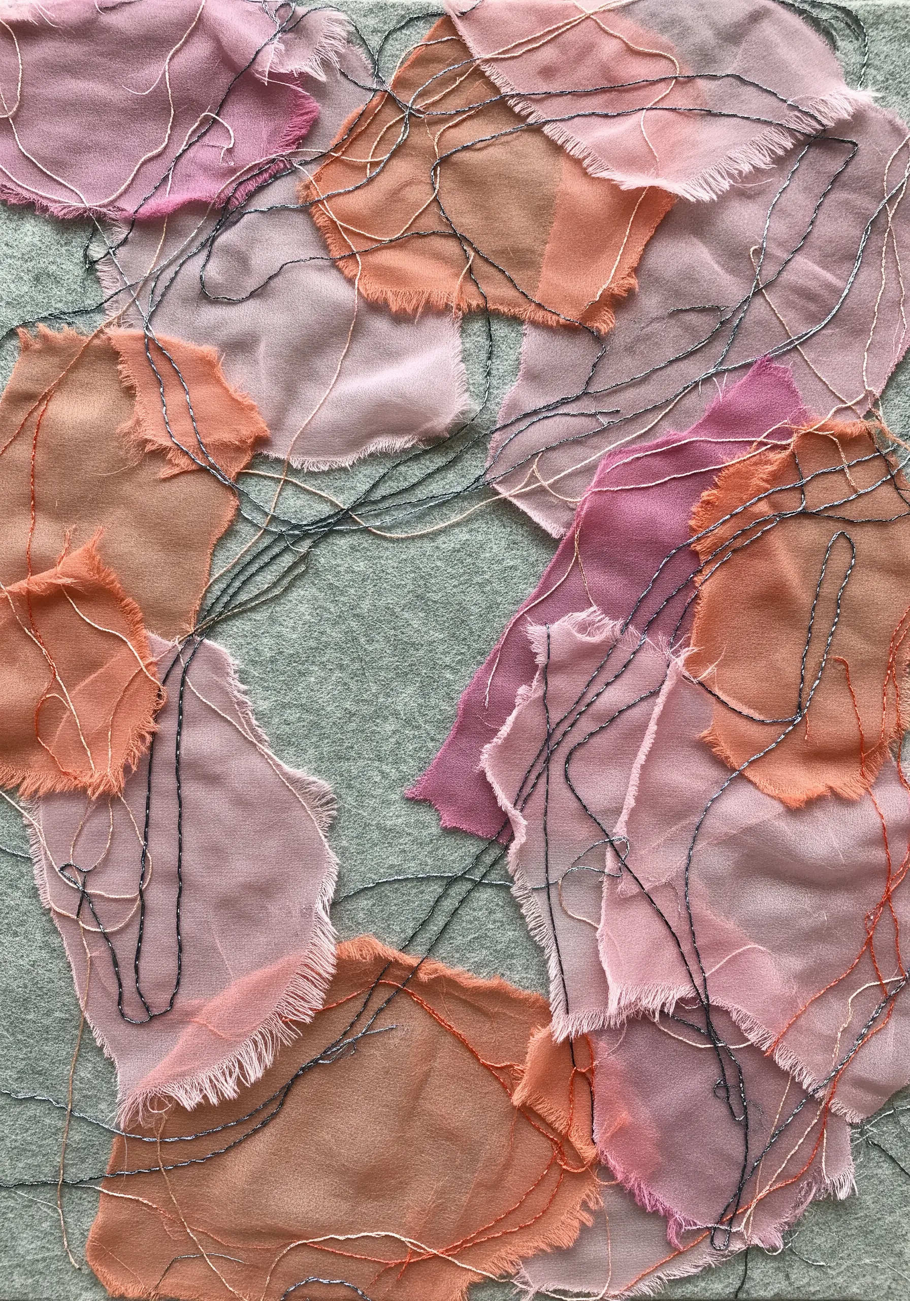 A fabric collage of frayed pink and orange sheer fabrics, overlaid with wandering black machine stitching.