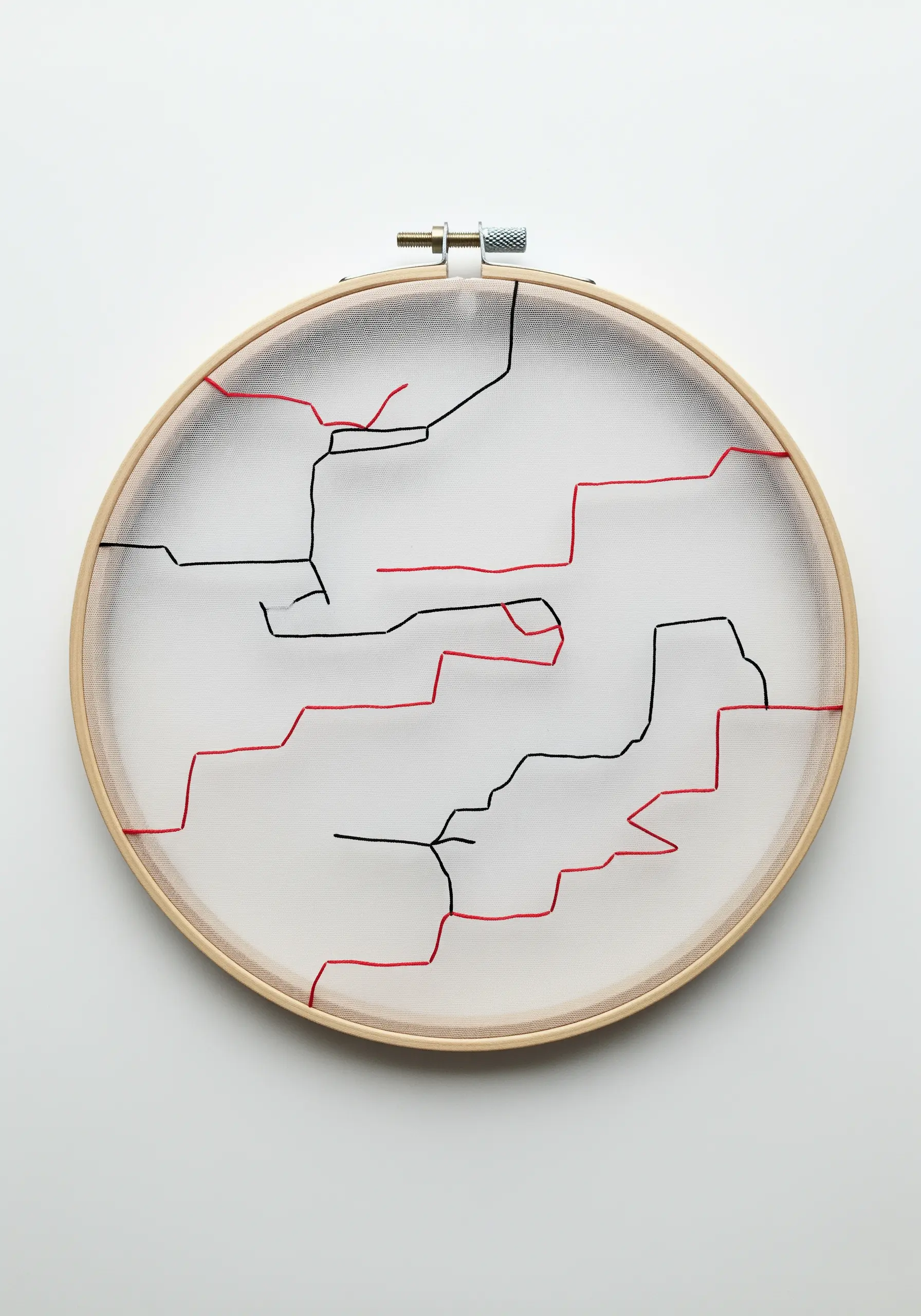 Minimalist red and black line art embroidered on sheer tulle fabric in a hoop.