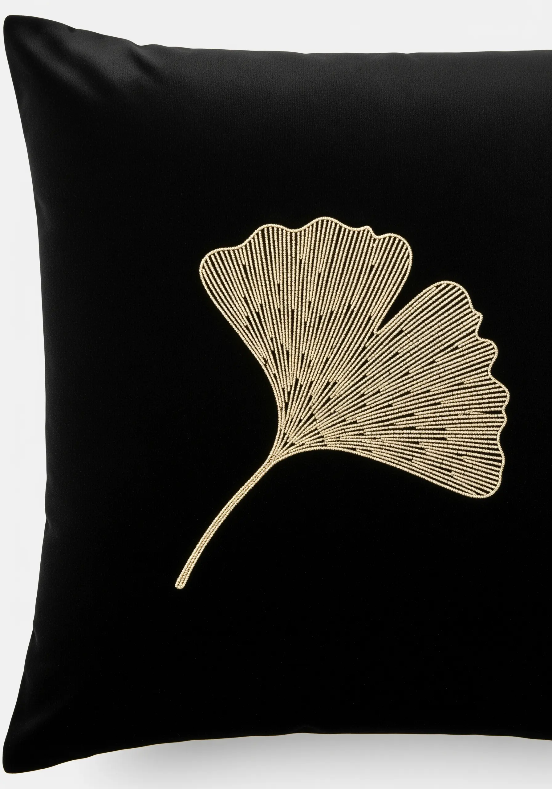 Gold seed stitch fills a ginkgo leaf outline on a black cushion.