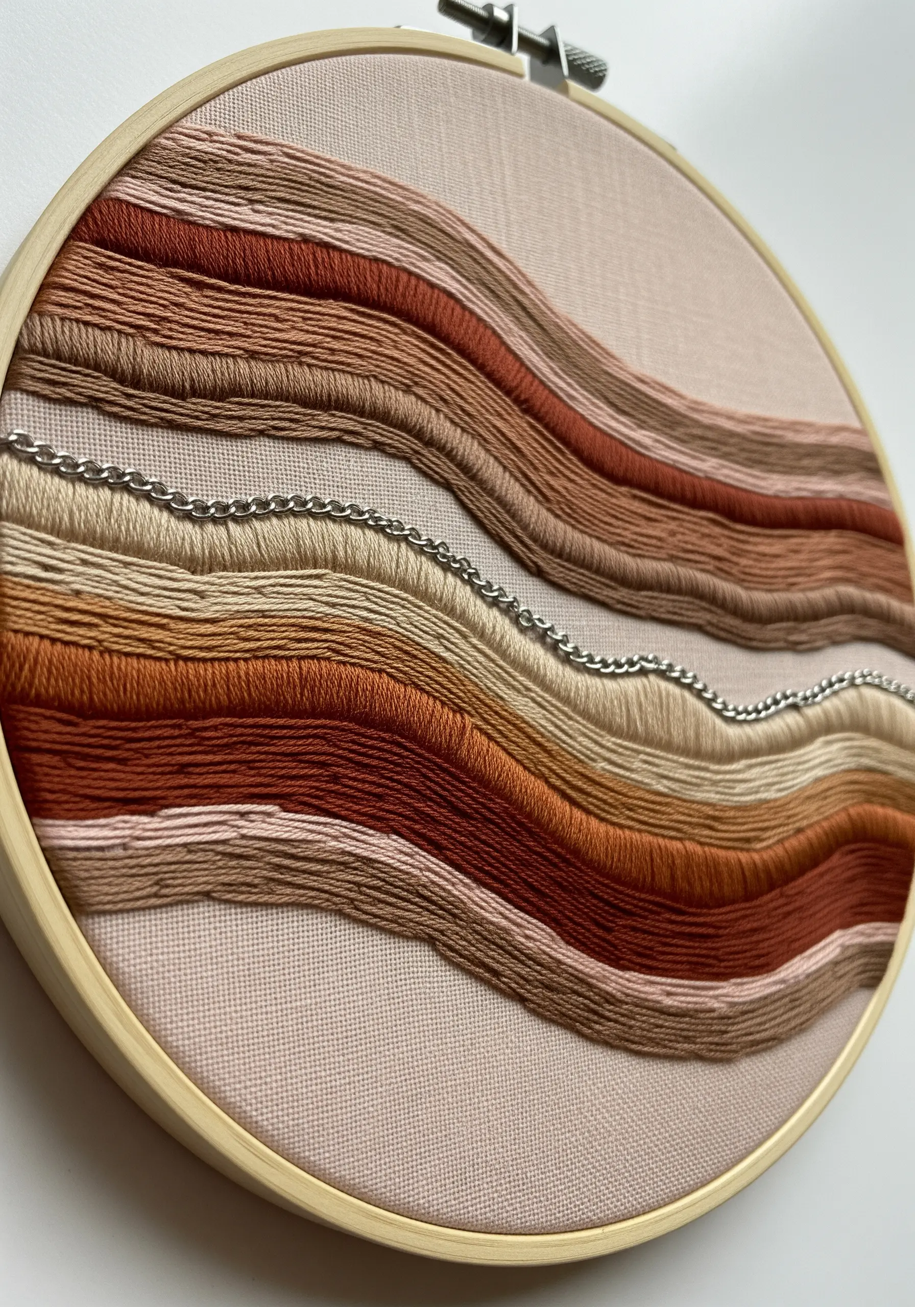 Wavy earth-toned embroidered lines with delicate silver chains stitched in between.