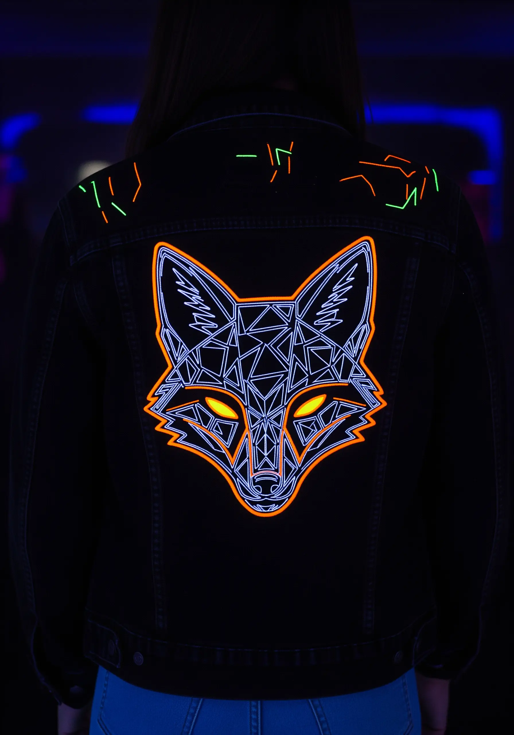 A geometric fox head in neon orange and white on the back of a black denim jacket.