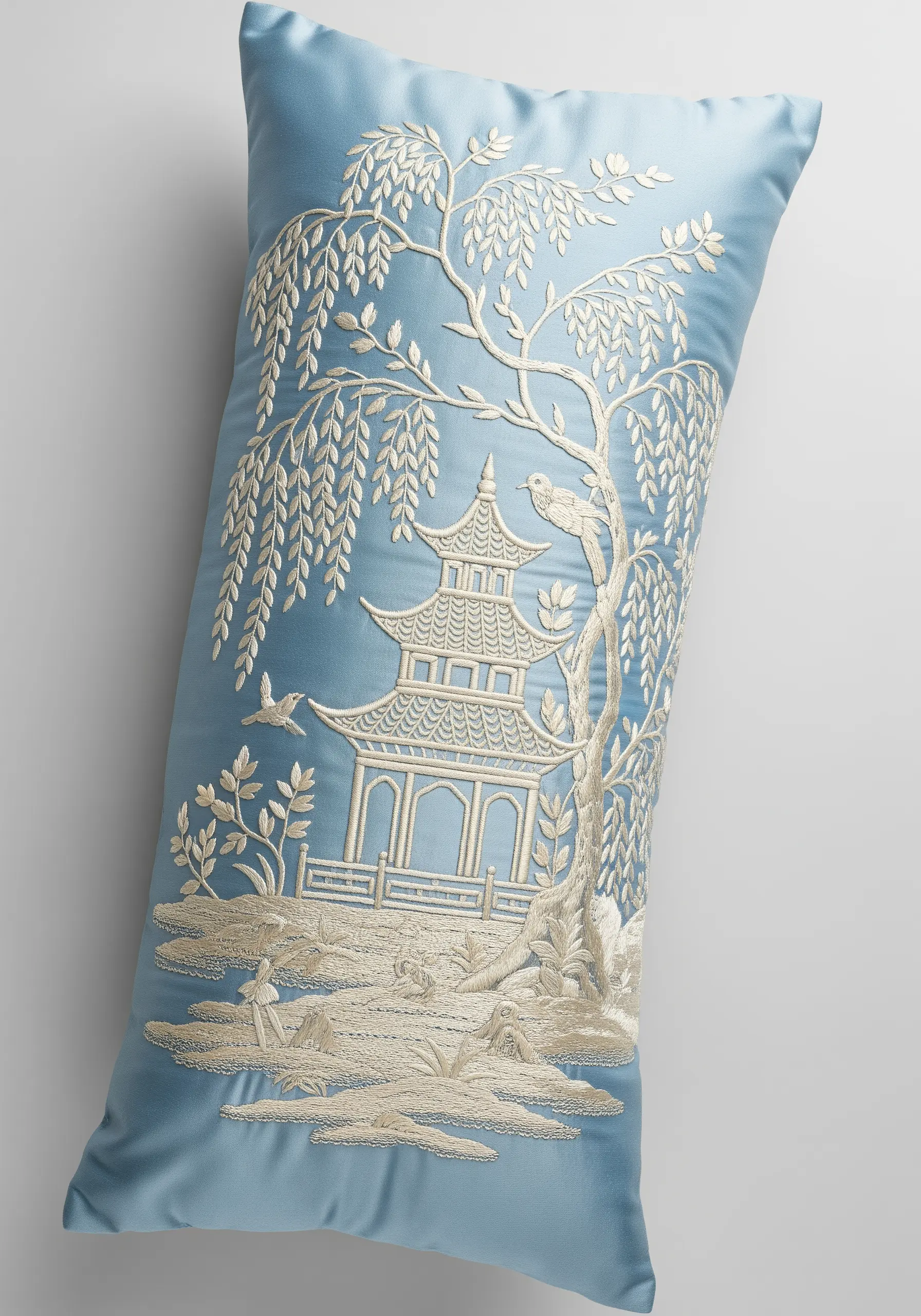 A cream-colored Chinoiserie landscape with a pagoda embroidered on a light blue cushion.