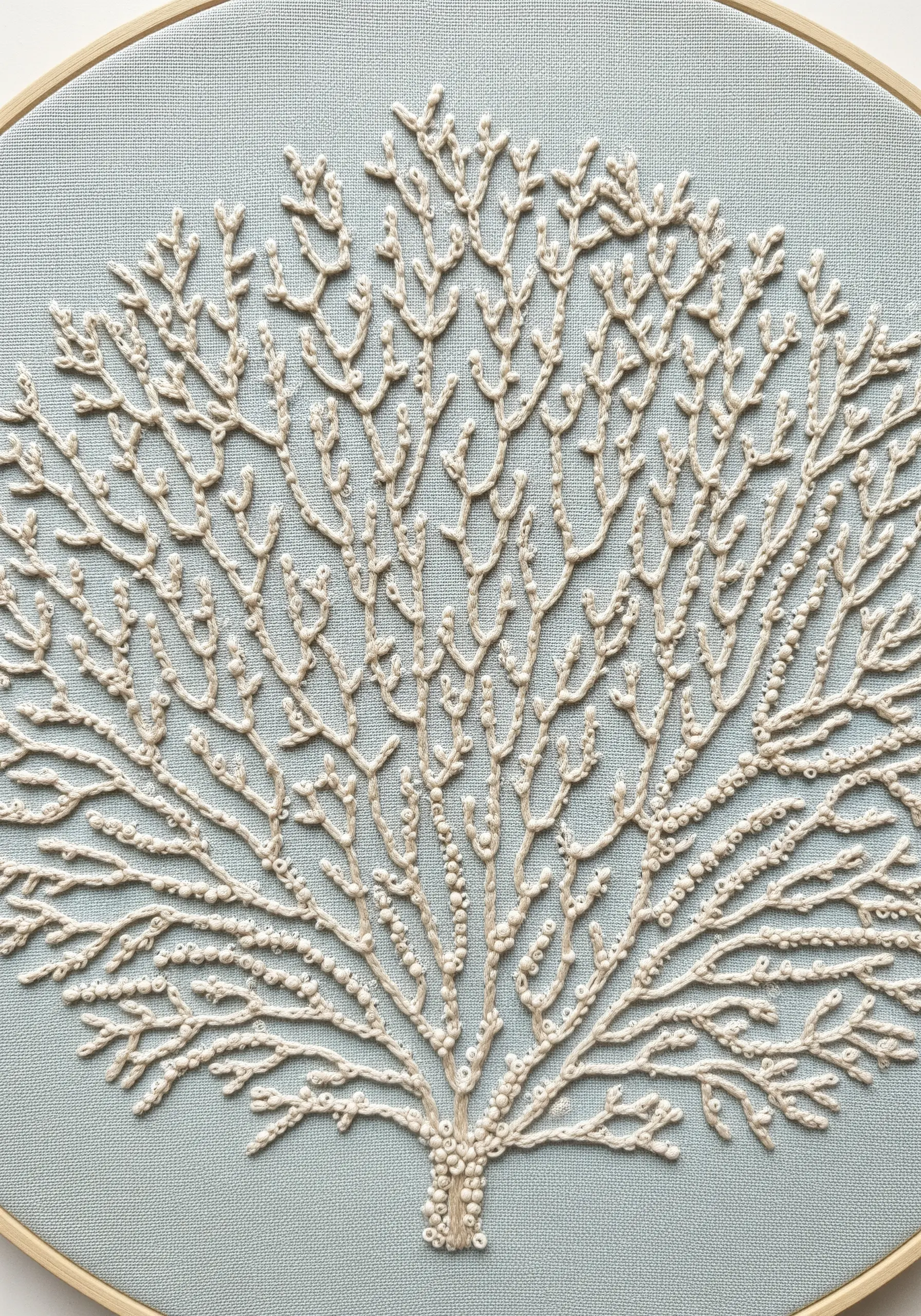 Delicate white coral embroidery on light blue fabric using stem stitch and French knots.