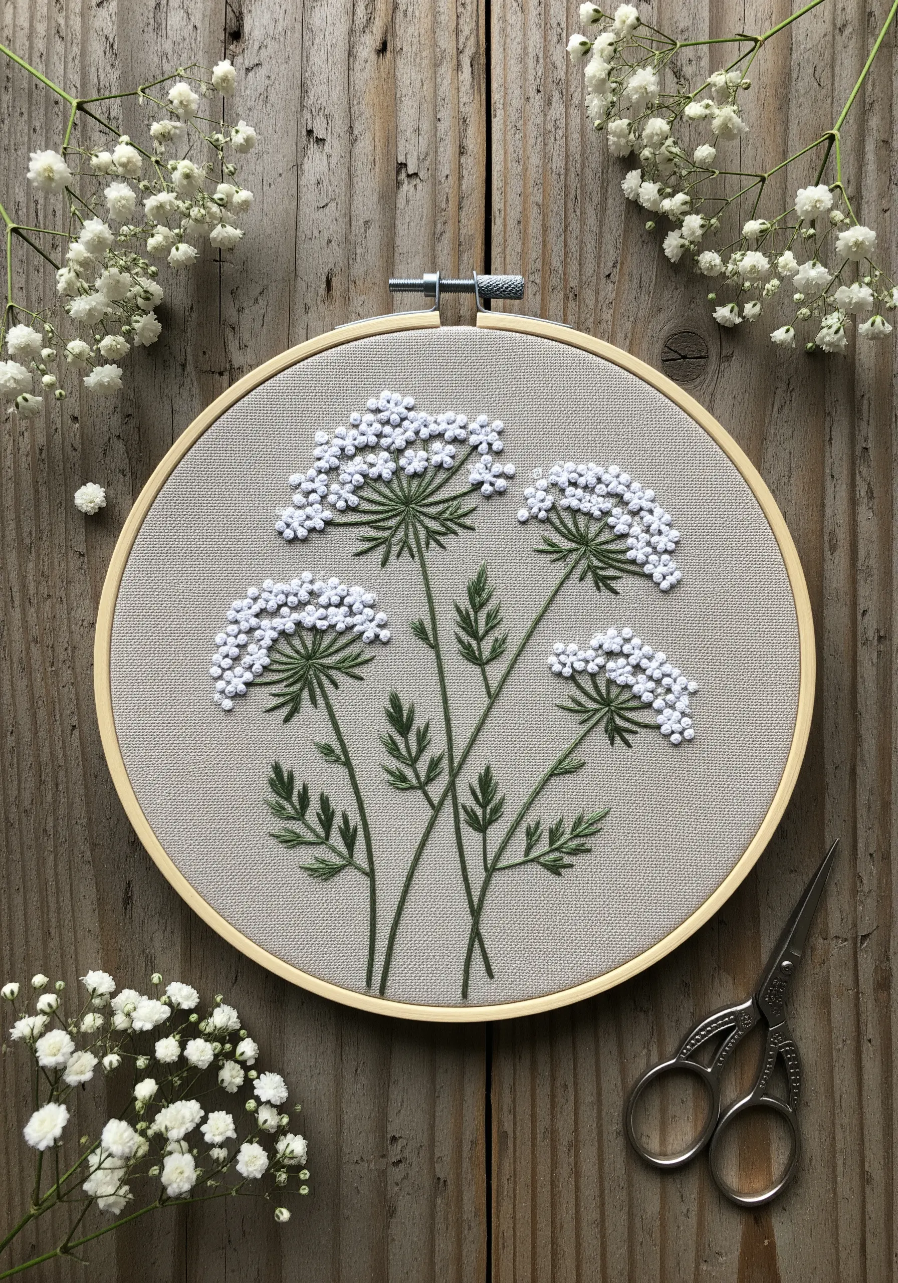 White French knots forming Queen Anne's Lace flowers on neutral linen fabric.