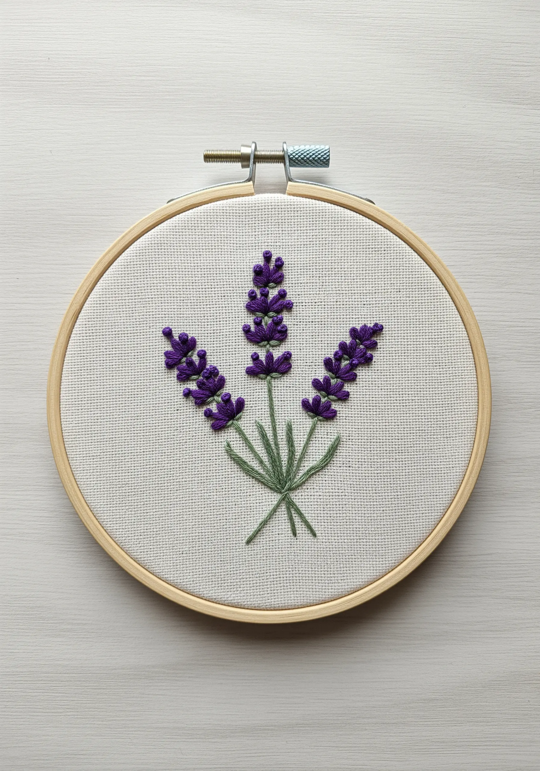 Embroidered lavender sprigs with textured French knots on white fabric.