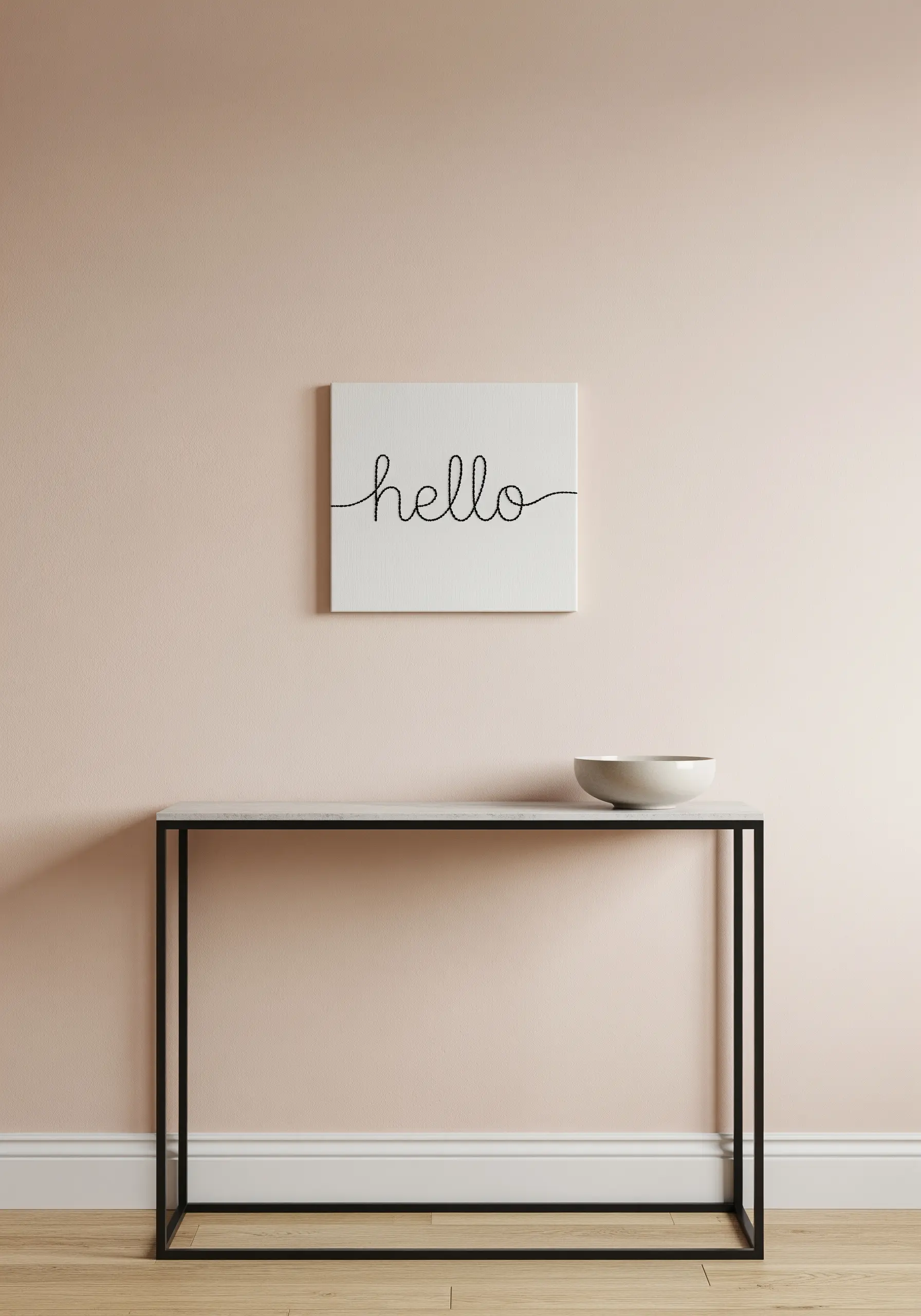A small white canvas with the word 'hello' embroidered in a simple, black cursive script.