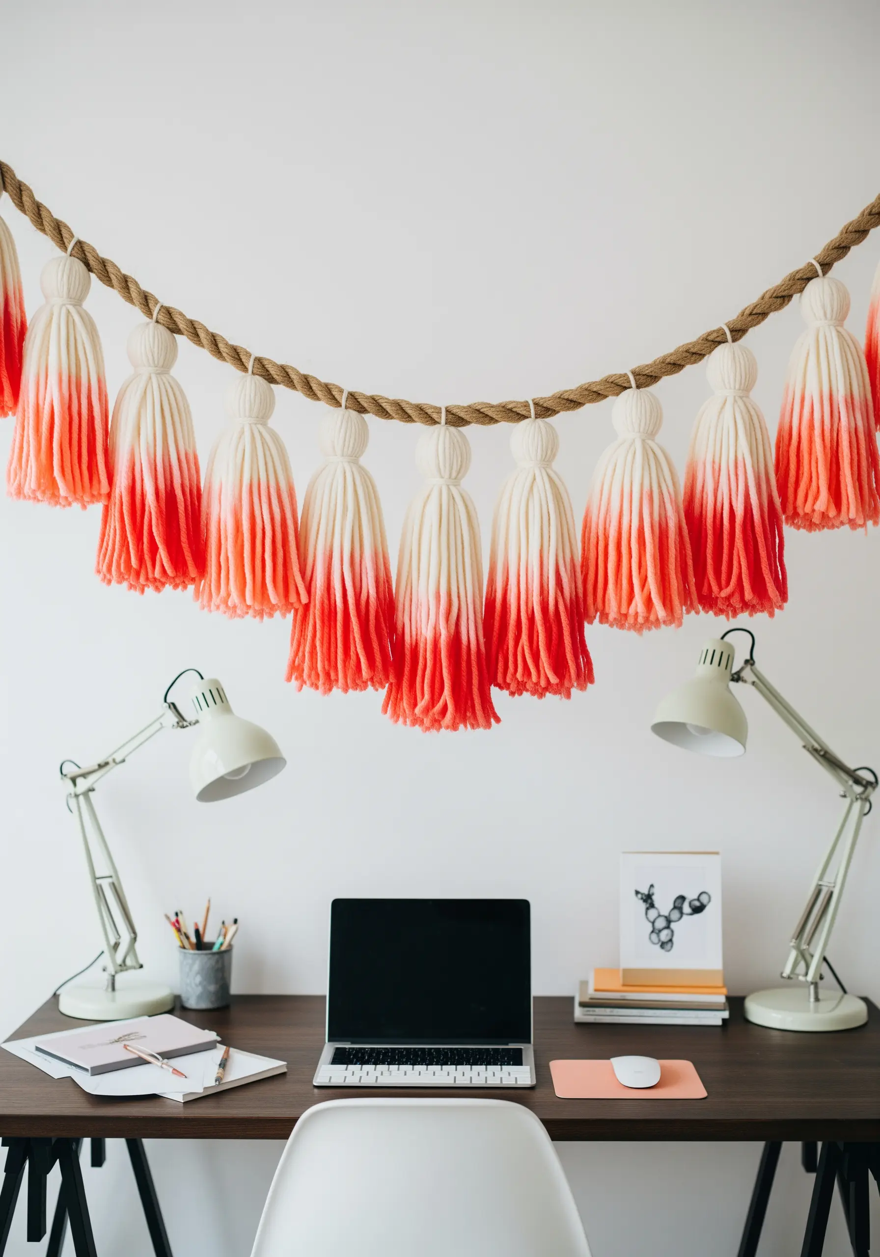 A garland of large, fluffy tassels dip-dyed with a vibrant coral-red gradient.