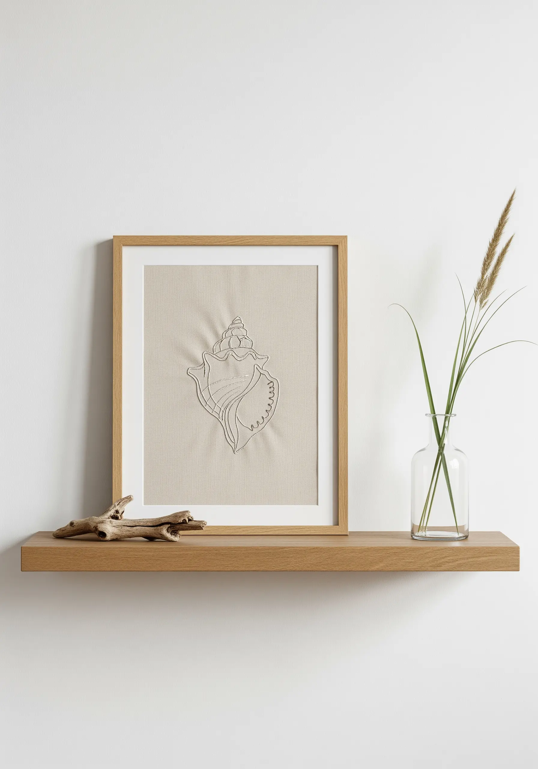 Minimalist line art embroidery of a conch shell on neutral linen fabric in a light wood frame.