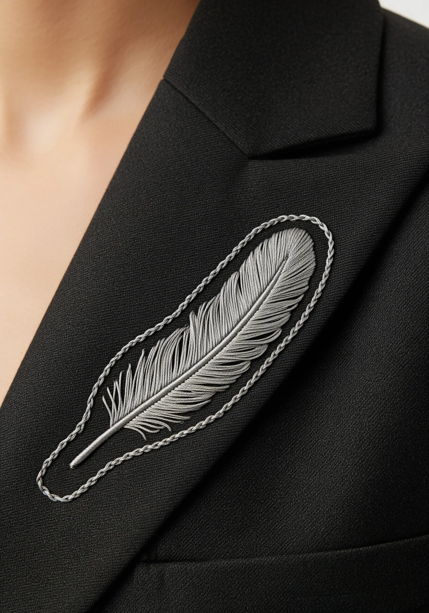 A detailed silver feather embroidered on the lapel of a black blazer, with a raised outline.