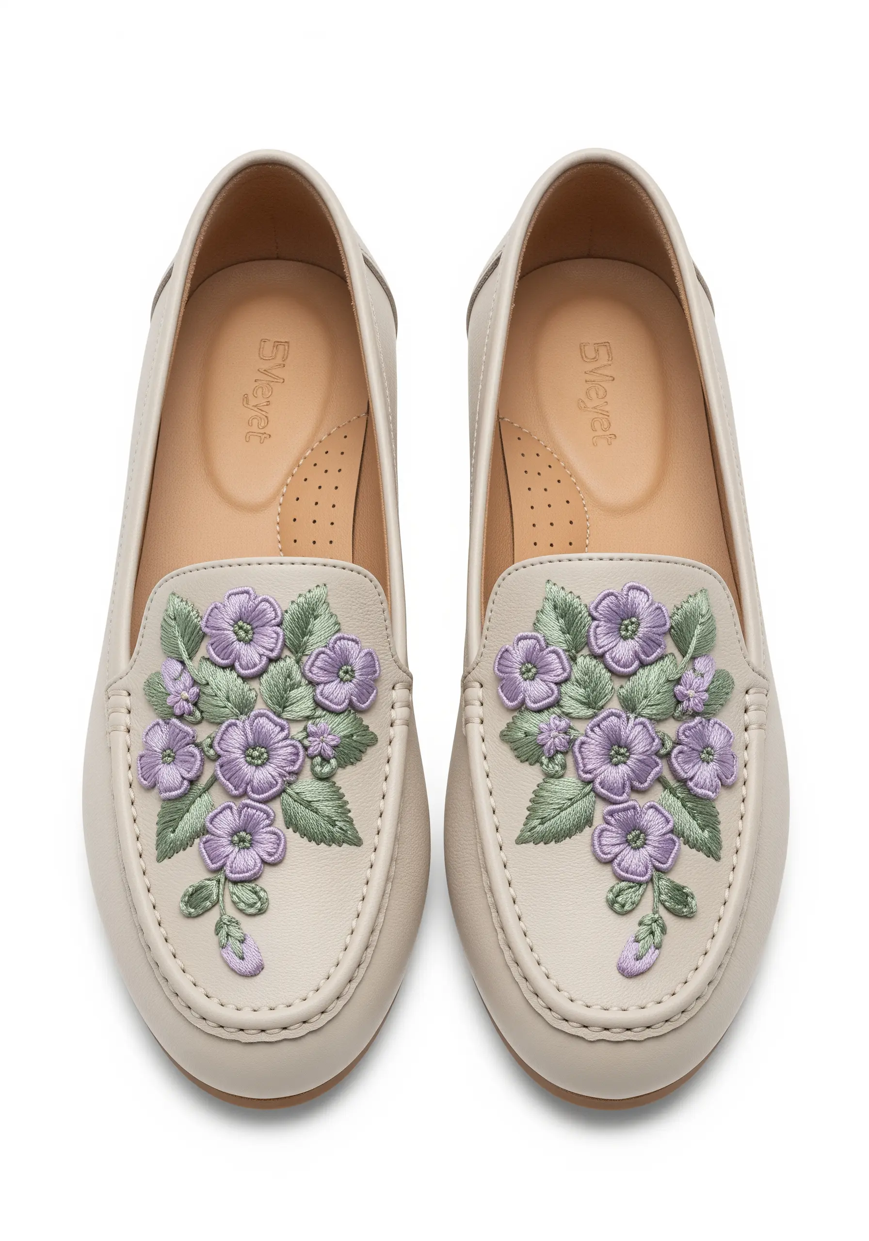 Delicate purple and green floral embroidery on the top of a pair of cream-colored leather loafers.