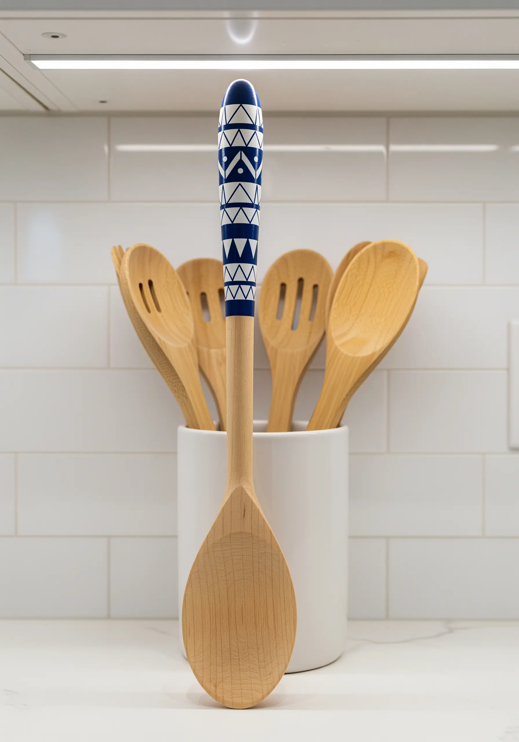 The handle of a wooden spoon painted with a blue and white geometric pattern.