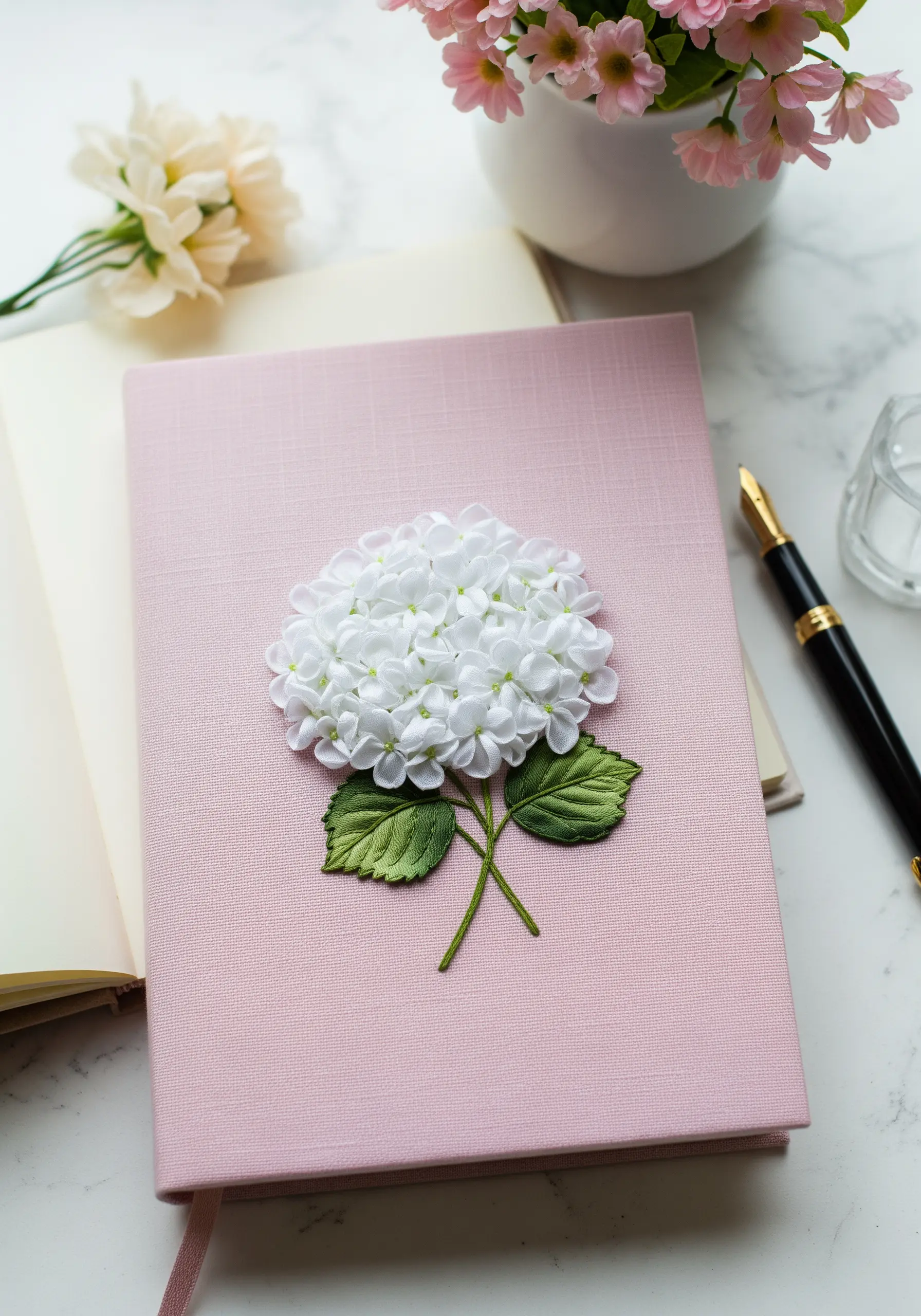 A dimensional white hydrangea made from silk ribbon embroidery on a pink journal cover.
