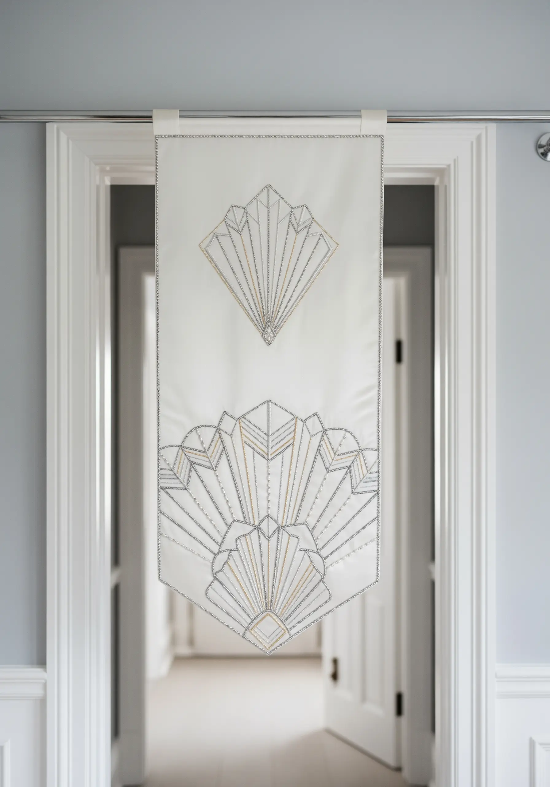 An Art Deco fan motif embroidered in silver and gold thread on a white banner.