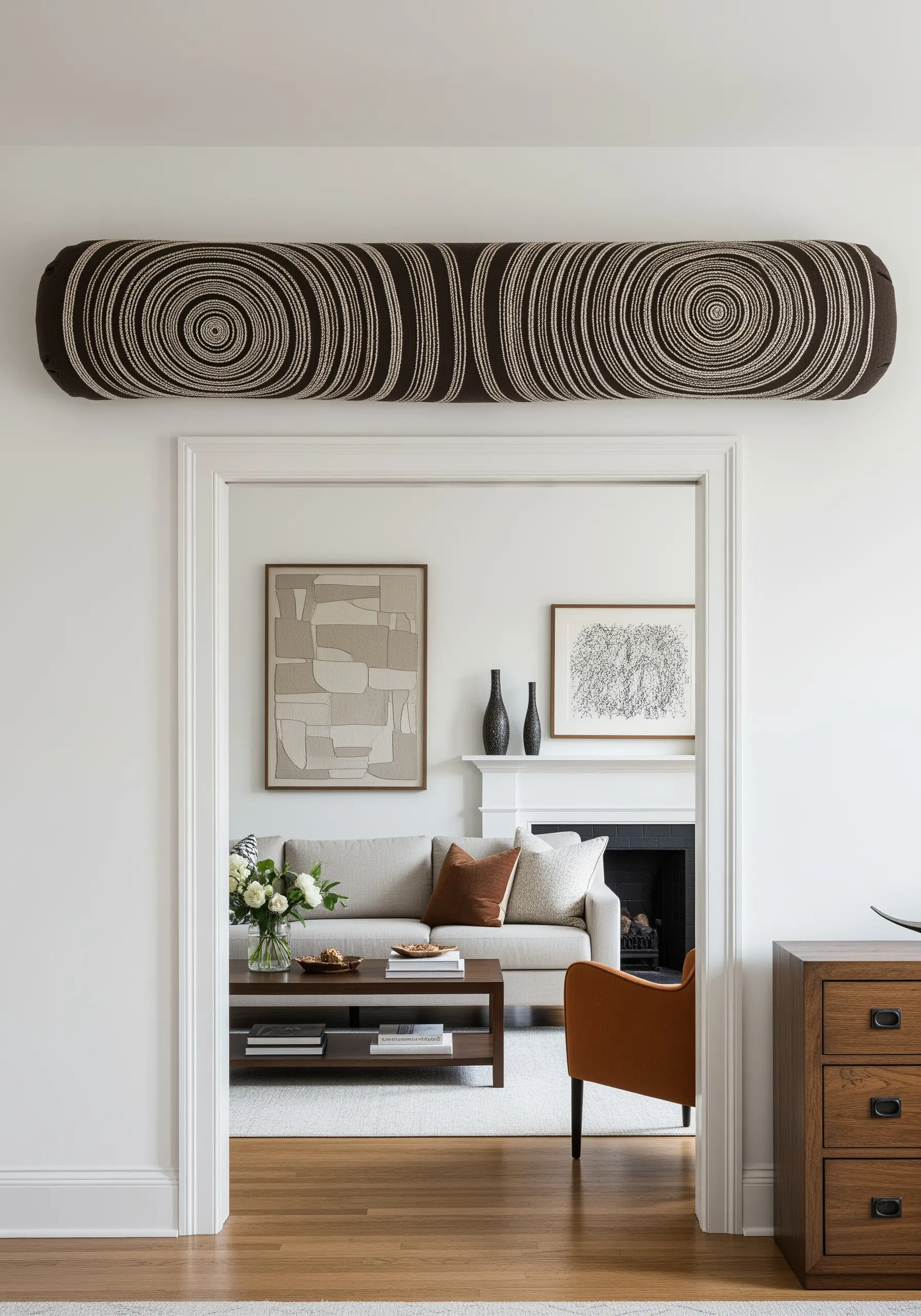 A long bolster pillow embroidered with concentric circles mimicking tree rings, hung over a doorway