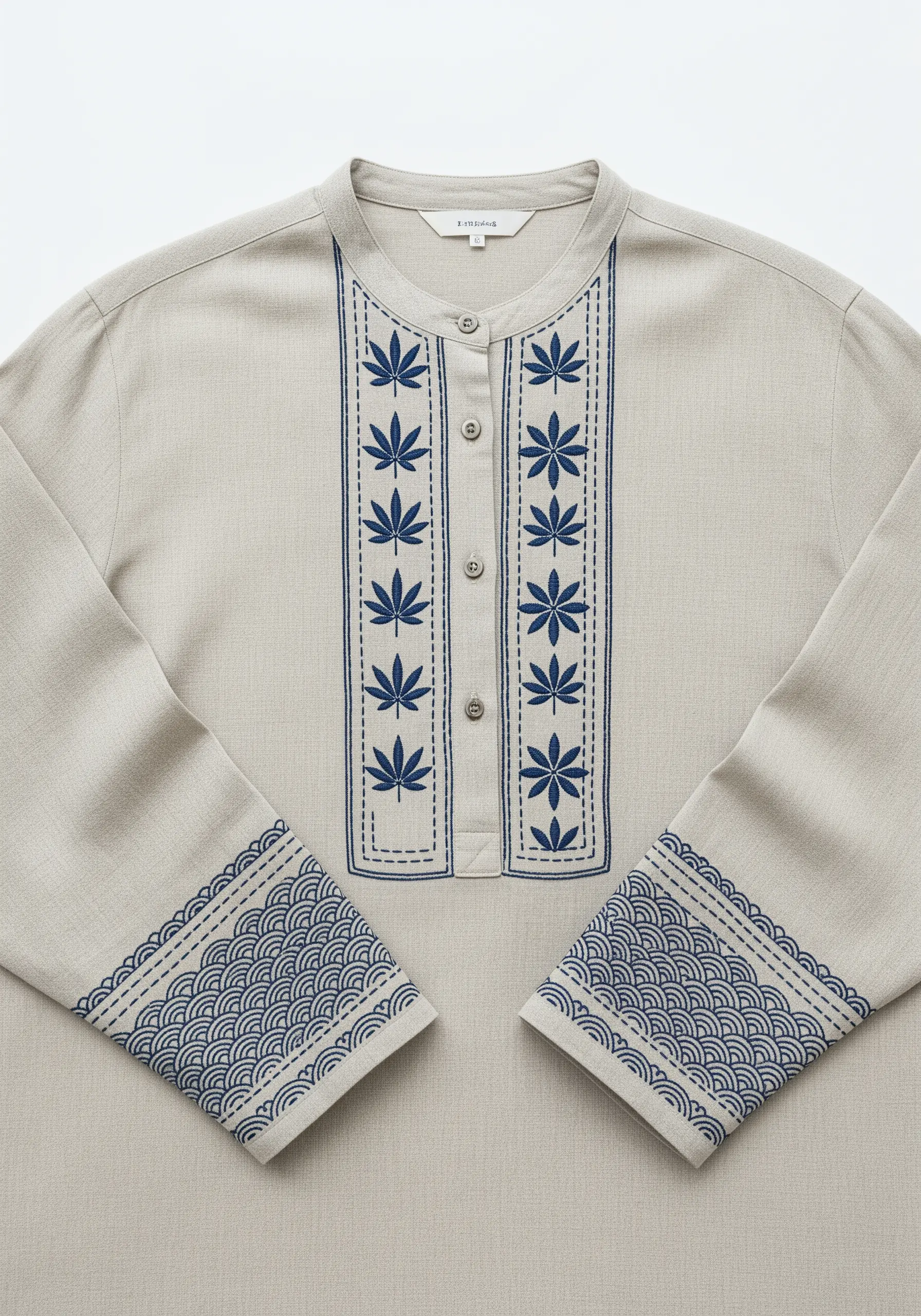 Minimalist blue embroidery on a linen shirt, featuring leaf motifs and a Japanese wave pattern.