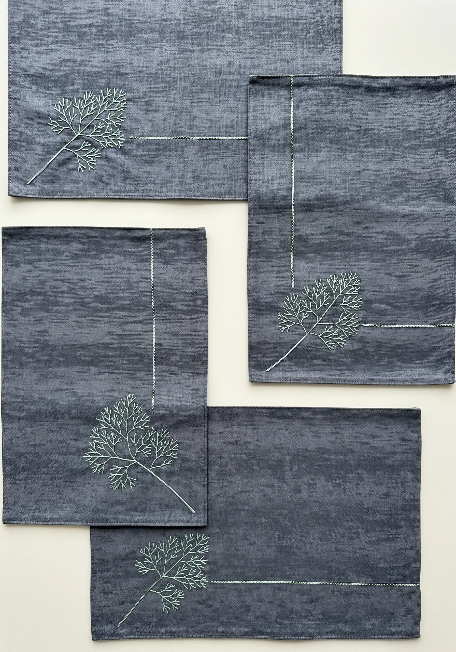 Minimalist light green dill sprigs embroidered on a set of dark gray placemats.
