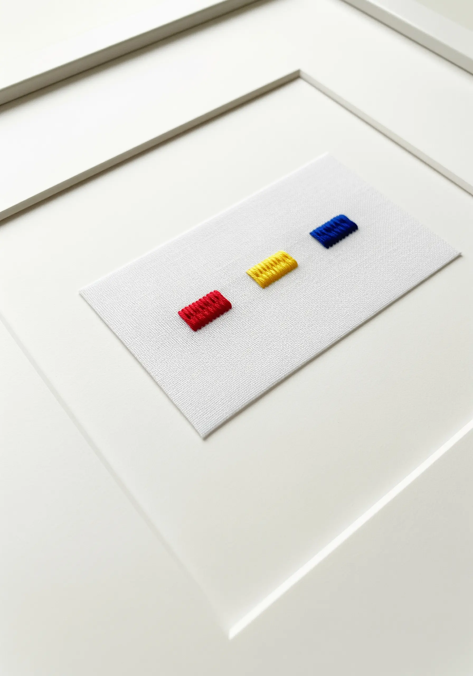 Three small, perfect rectangles of satin stitch in red, yellow, and blue.