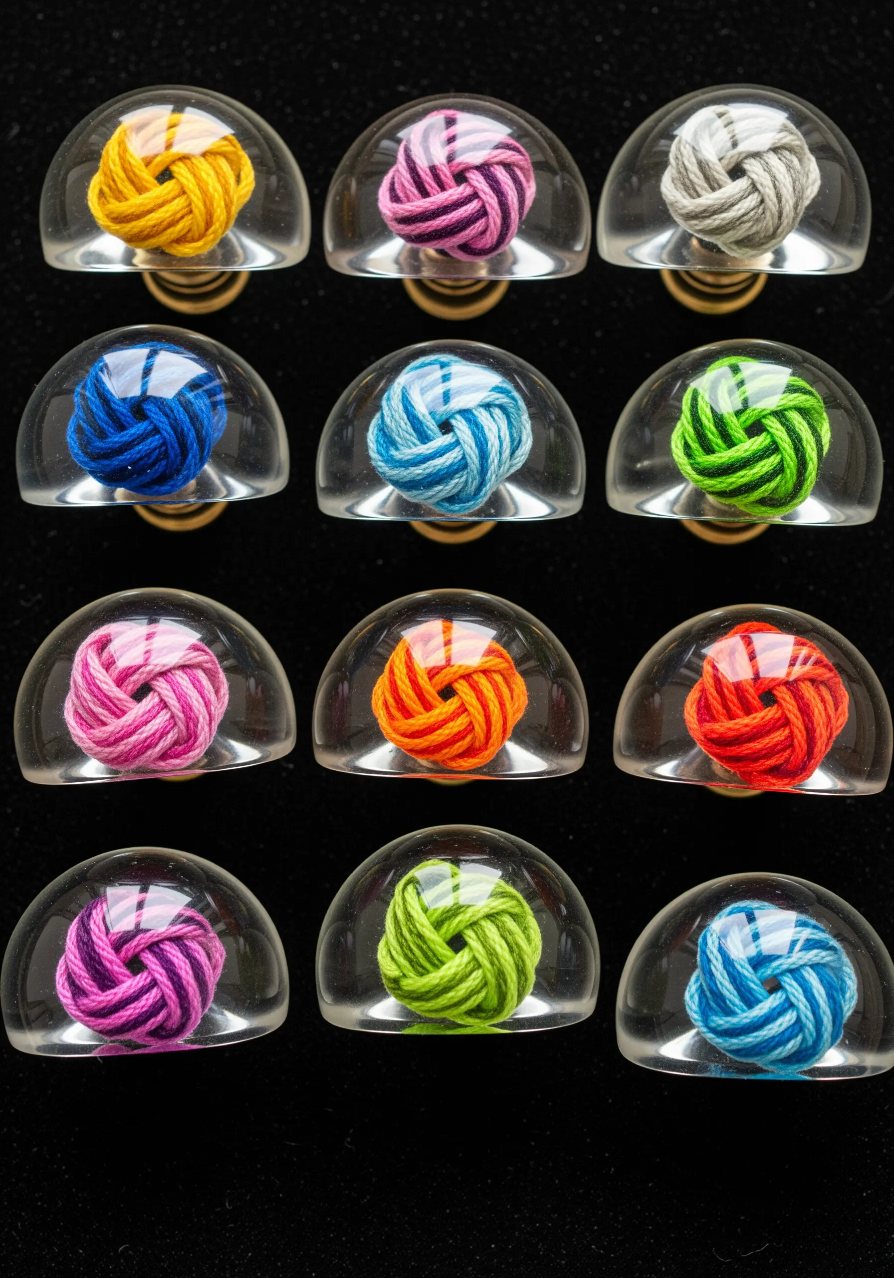 Colorful knotted threads preserved under clear, dome-shaped resin for drawer knobs.