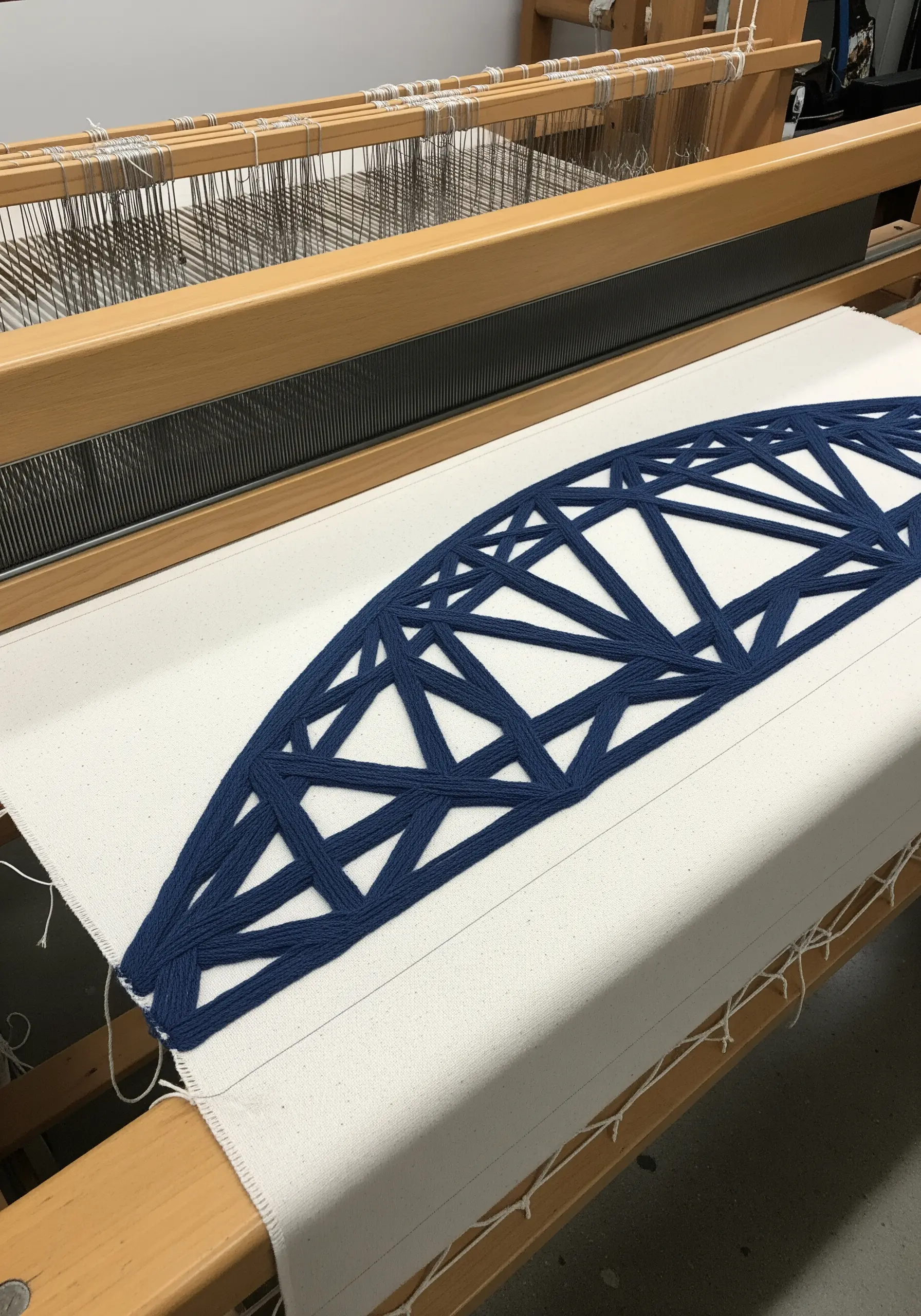 Blue geometric bridge truss embroidery on a loom