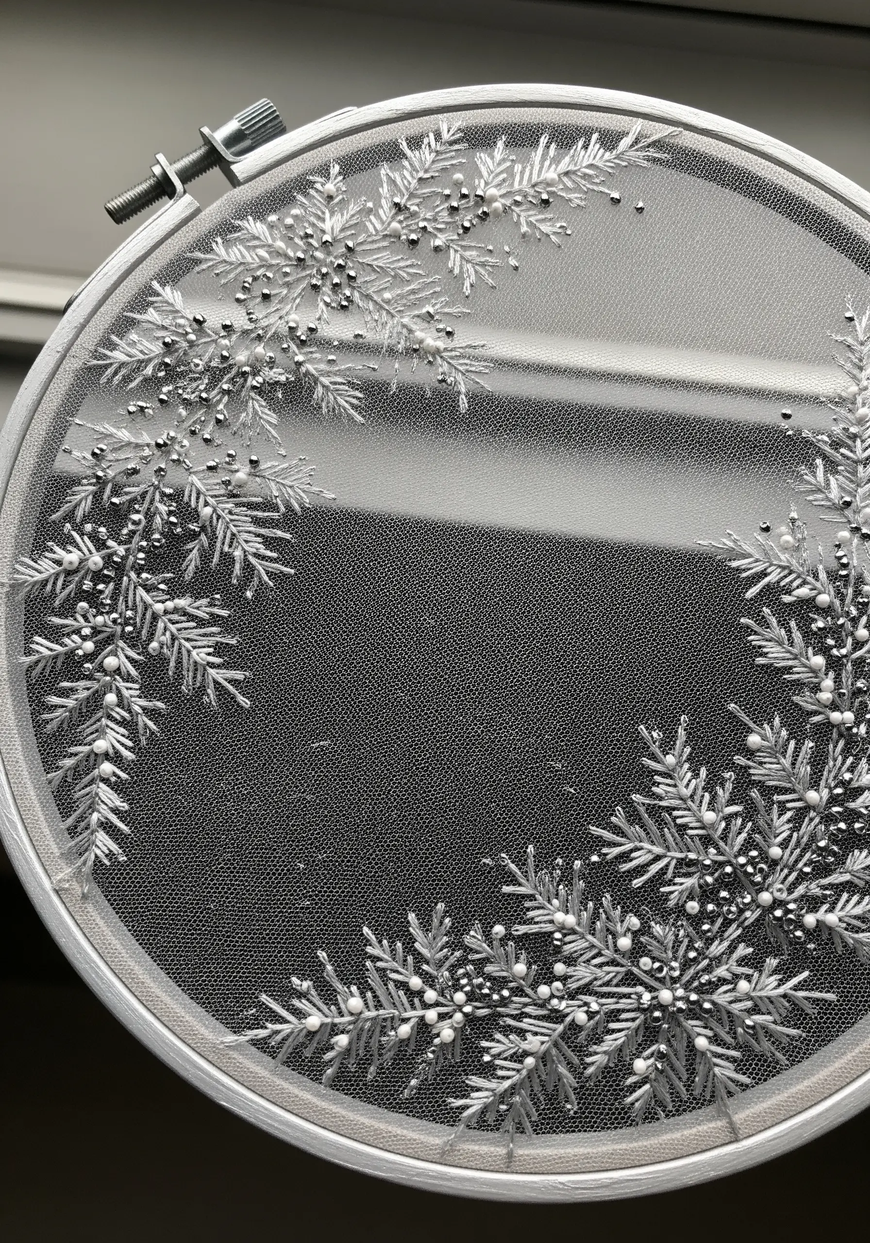 Delicate white and silver snowflake embroidery with beads on sheer tulle fabric.