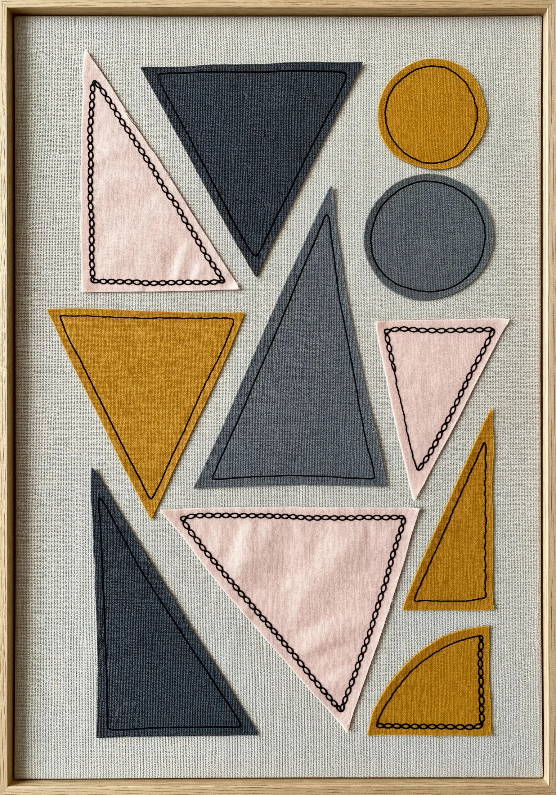 A minimalist composition of geometric fabric shapes outlined with decorative black stitches.