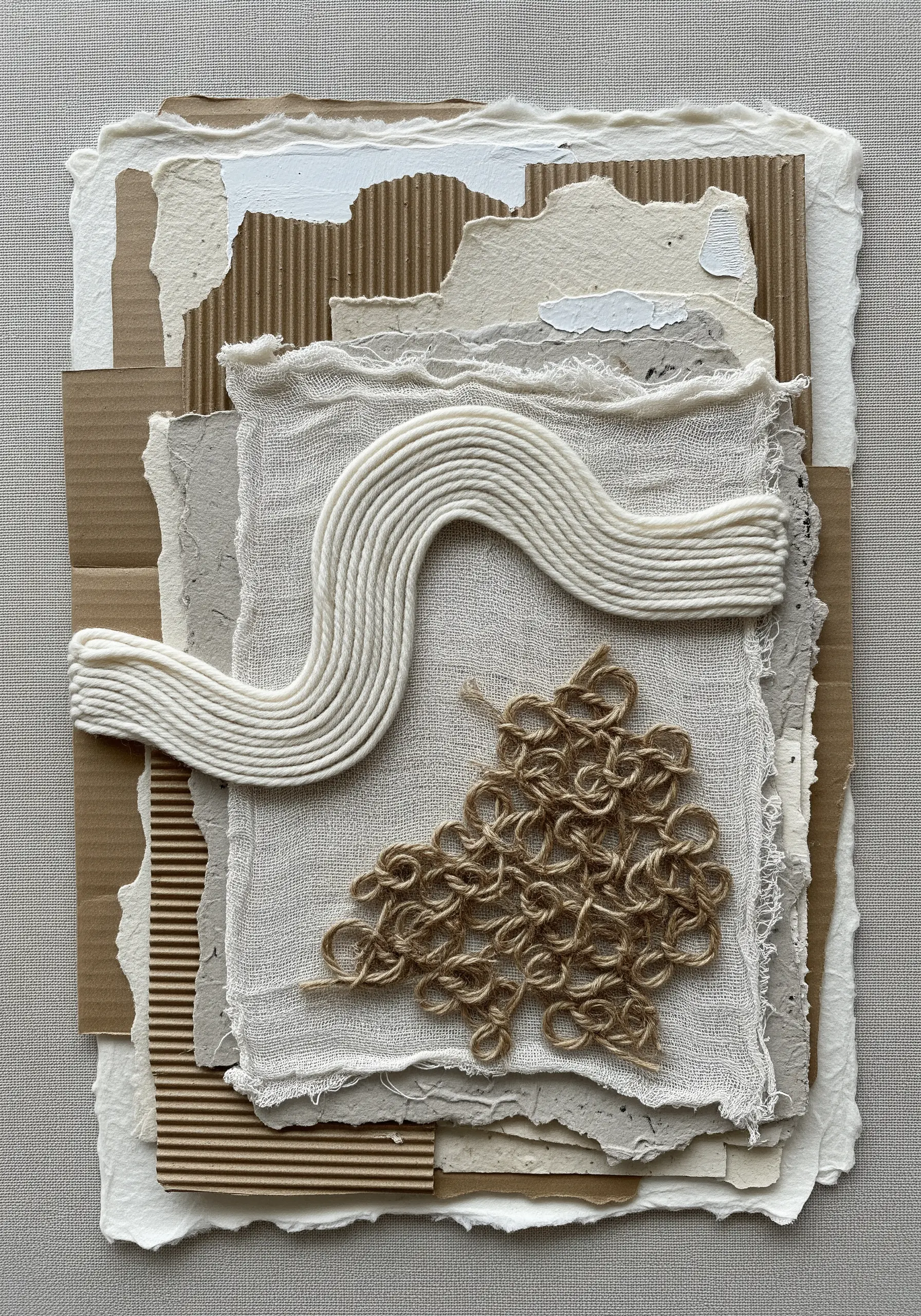 A neutral-toned collage of paper and fabric featuring heavily textured yarn embroidery.