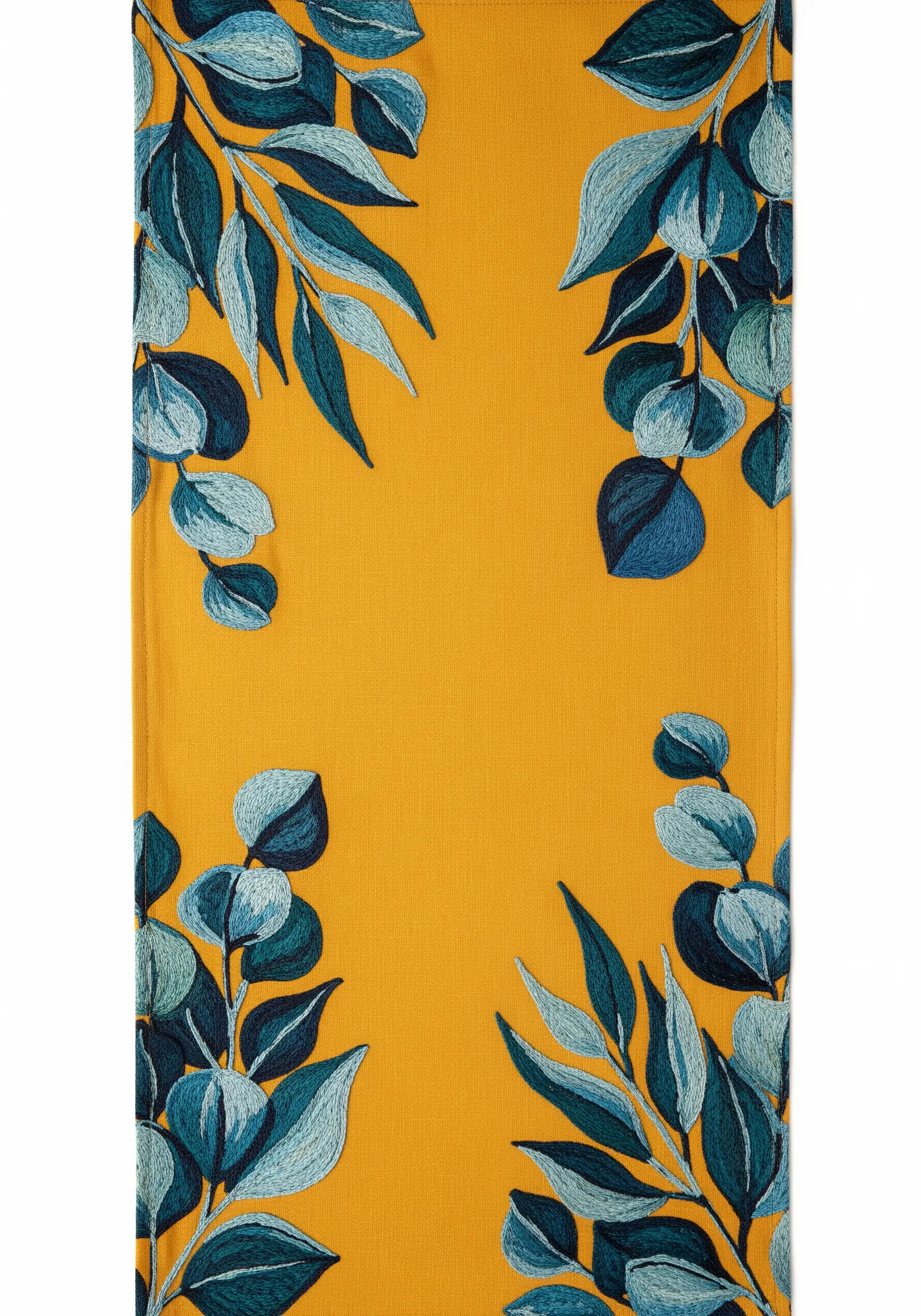 A table runner in mustard yellow with corners decorated with leaves in shades of blue and teal.