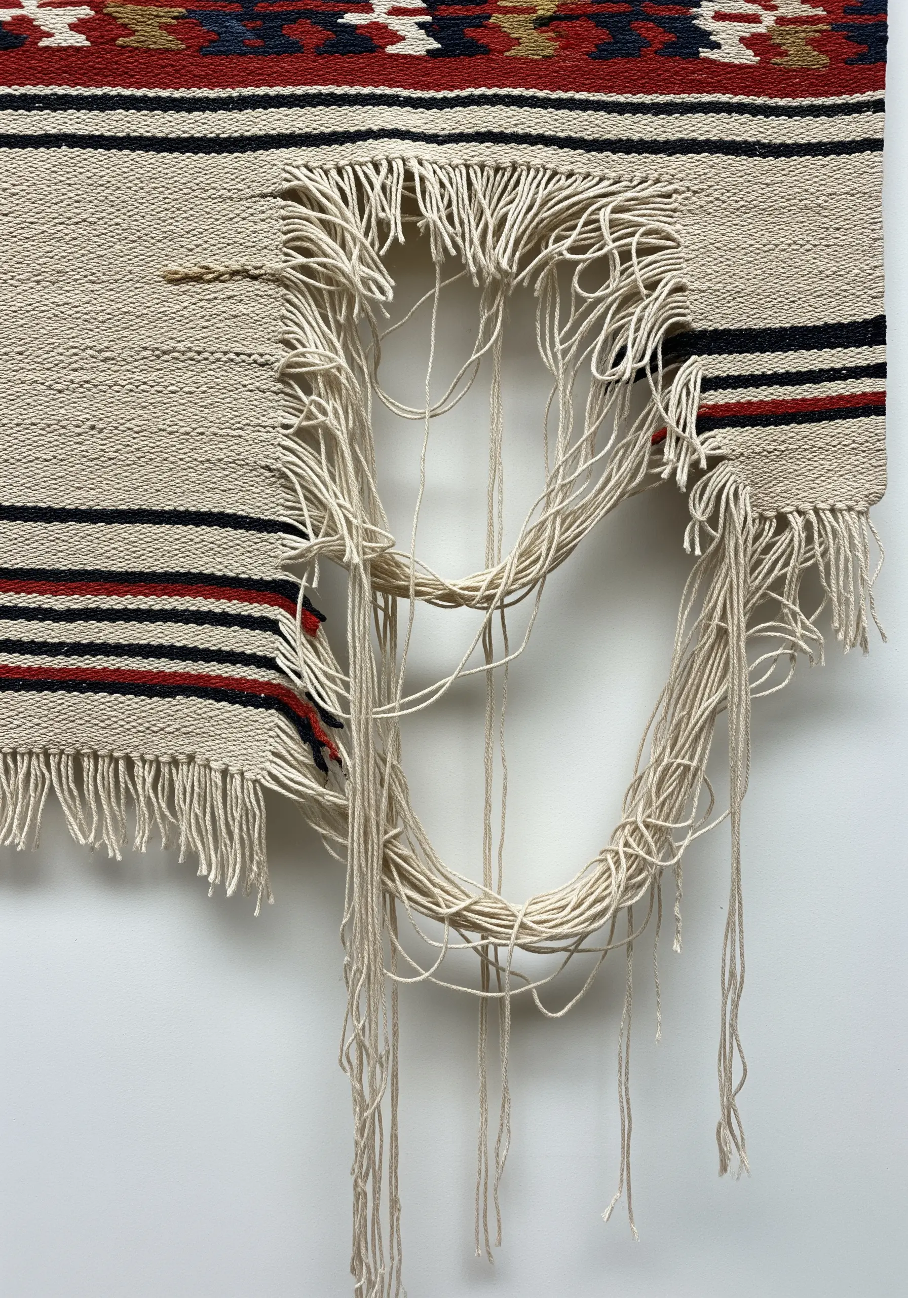 A woven tapestry with a large, deconstructed circular hole showing loose warp threads.