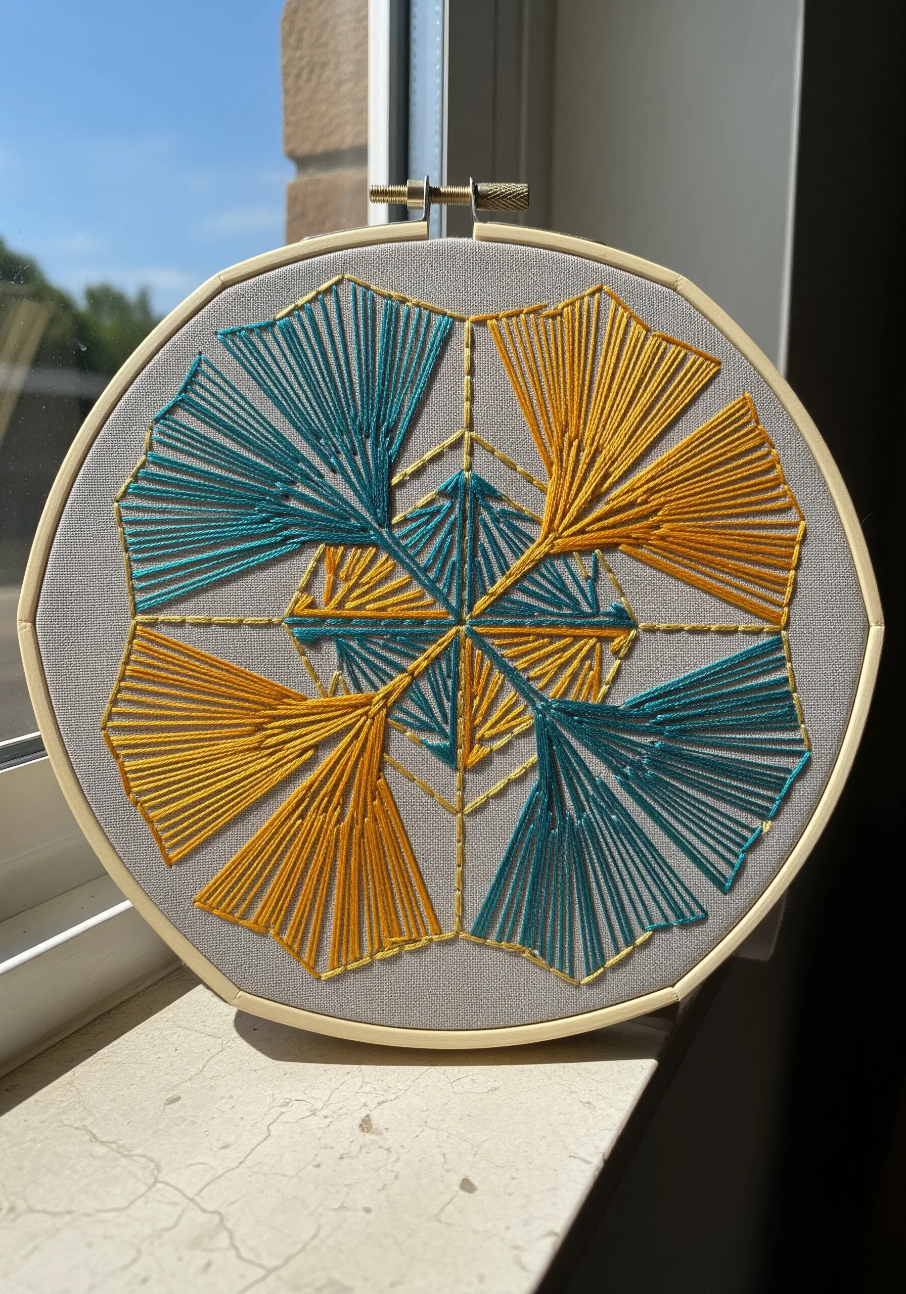 A geometric pattern of teal and yellow embroidered ginkgo leaves.
