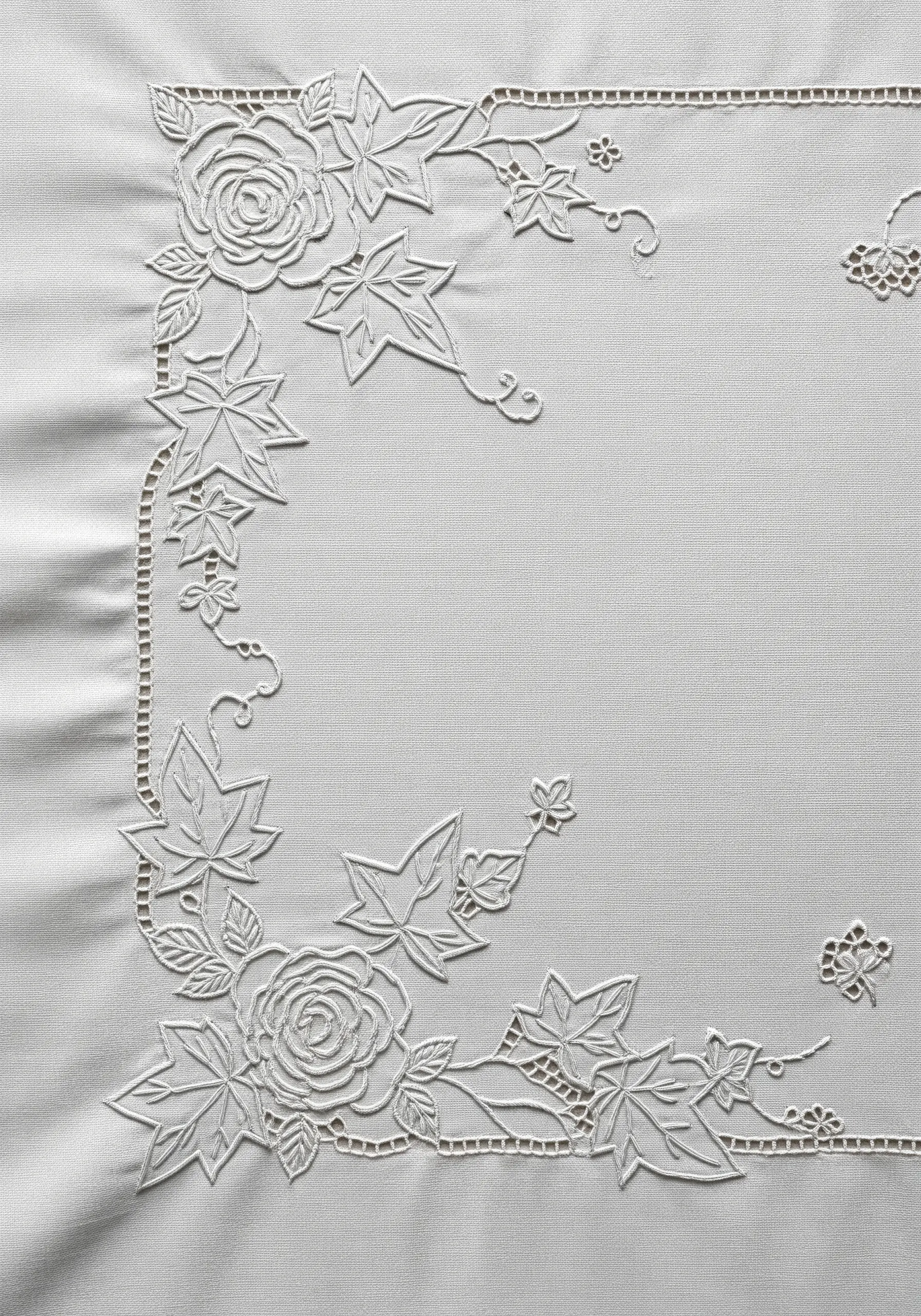An elegant white-on-white embroidery corner design with cutwork details creating lace-like effects.