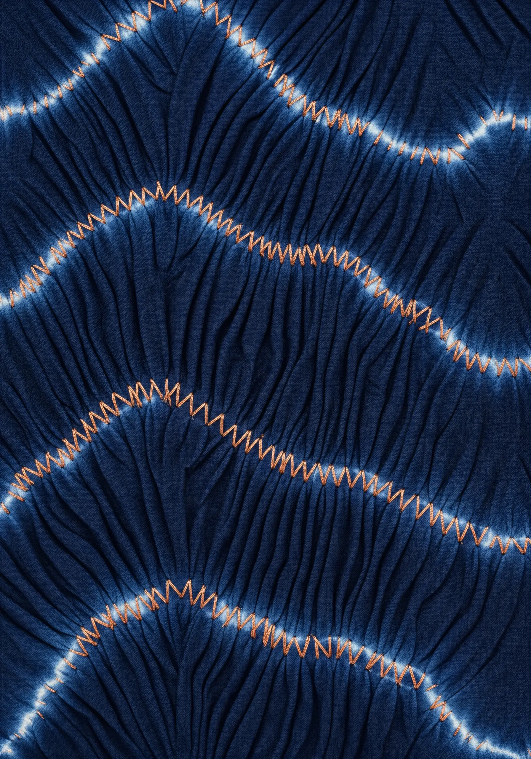 Deep blue fabric gathered into tight pleats with contrasting orange zigzag stitches.
