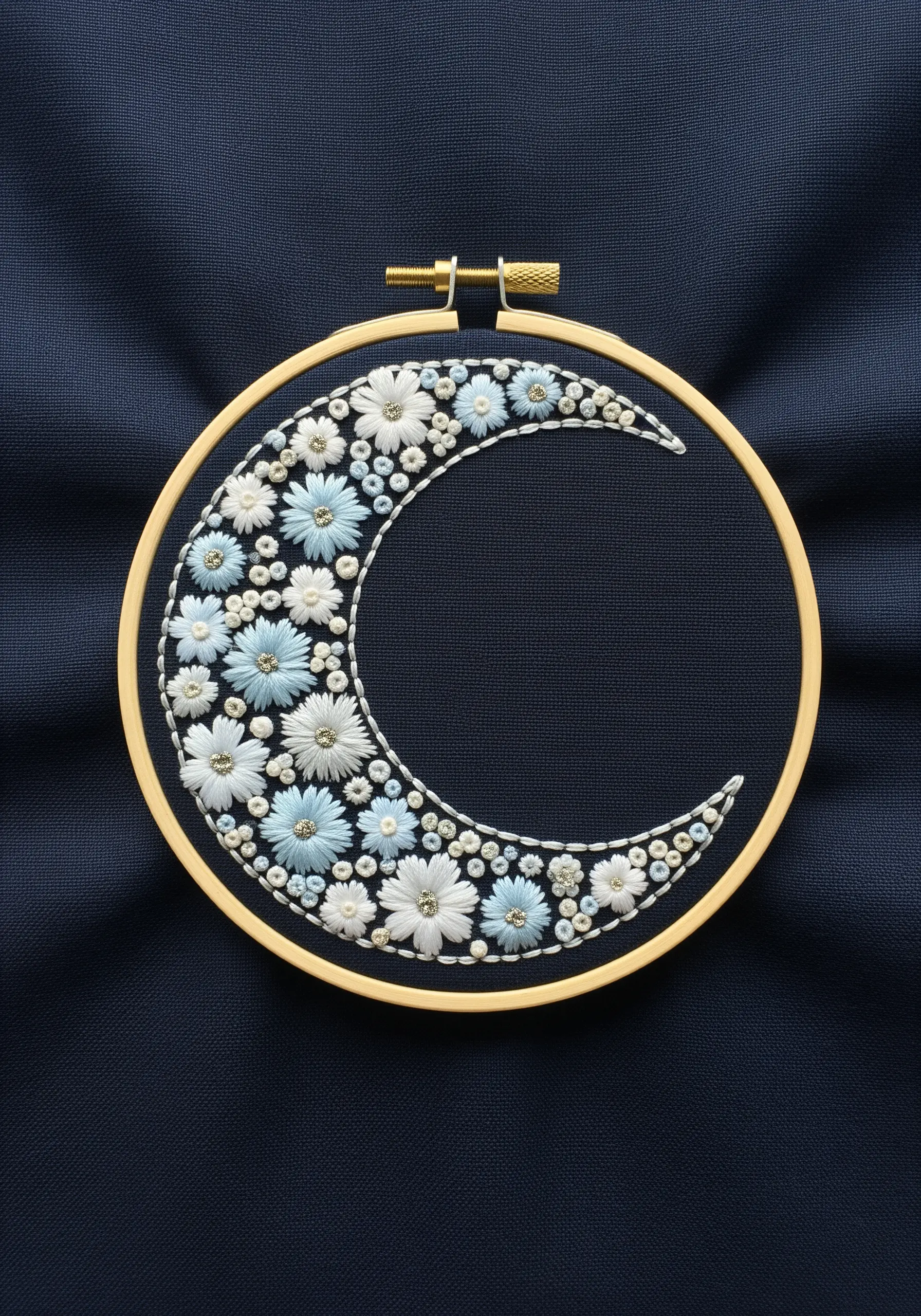 A crescent moon shape filled with tiny white and blue embroidered flowers on dark navy fabric.
