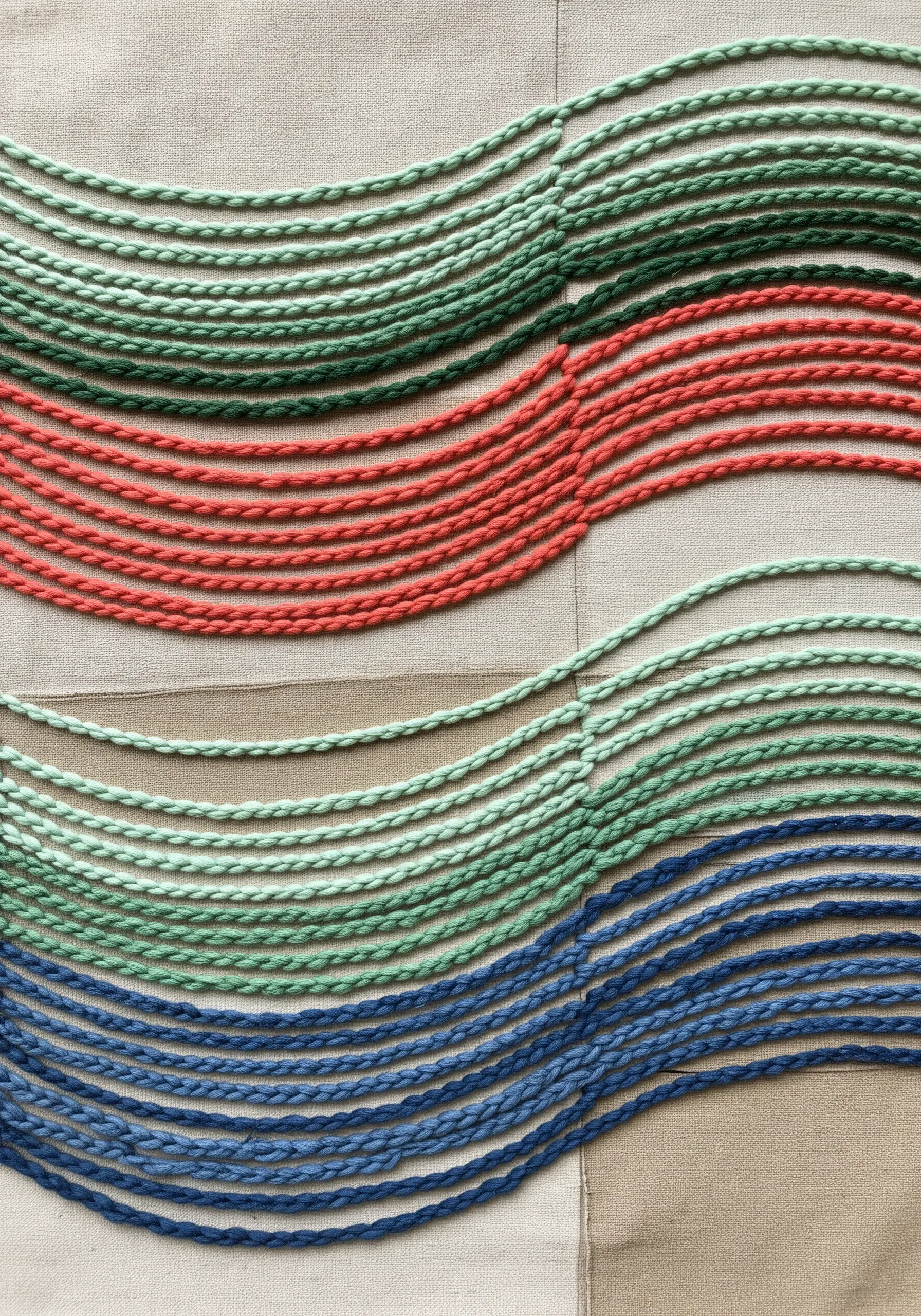 Abstract wavy lines made from braided embroidery floss in shades of green, coral, and blue.