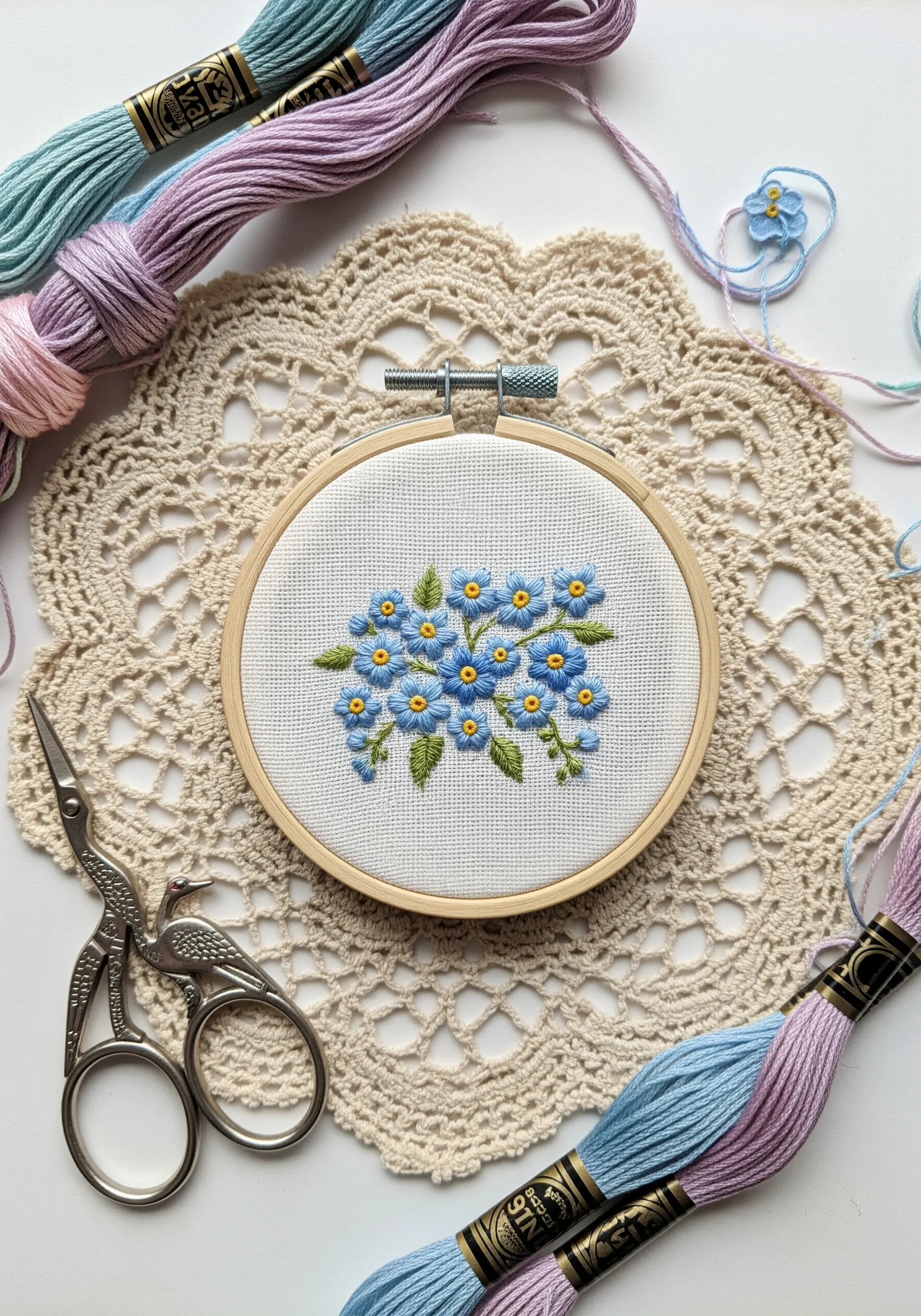 A cluster of embroidered blue forget-me-not flowers made with lazy daisy stitches.