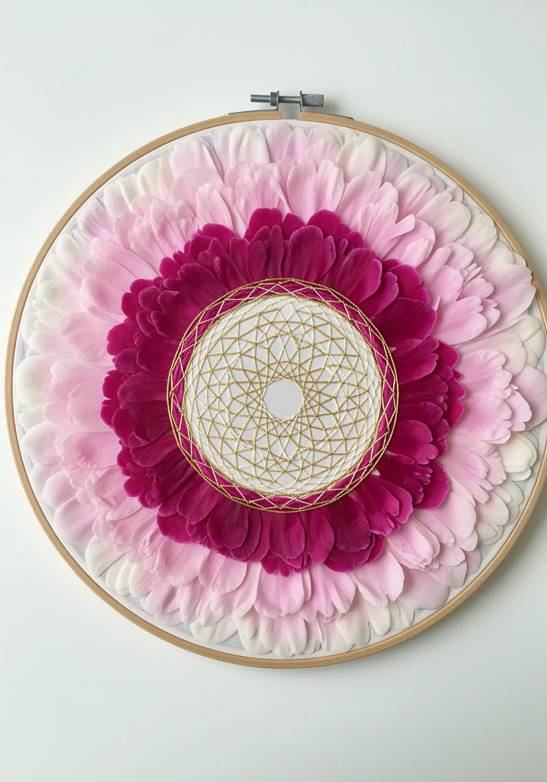 A mandala of pink flower petals surrounding a geometric gold string art center.