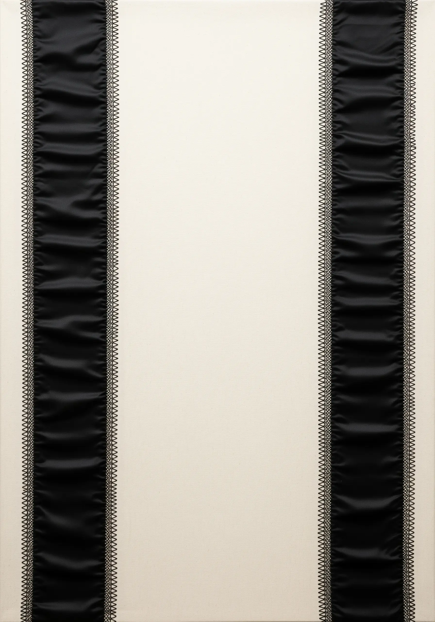 Two vertical black satin ribbons framed by delicate stitching on a cream background.