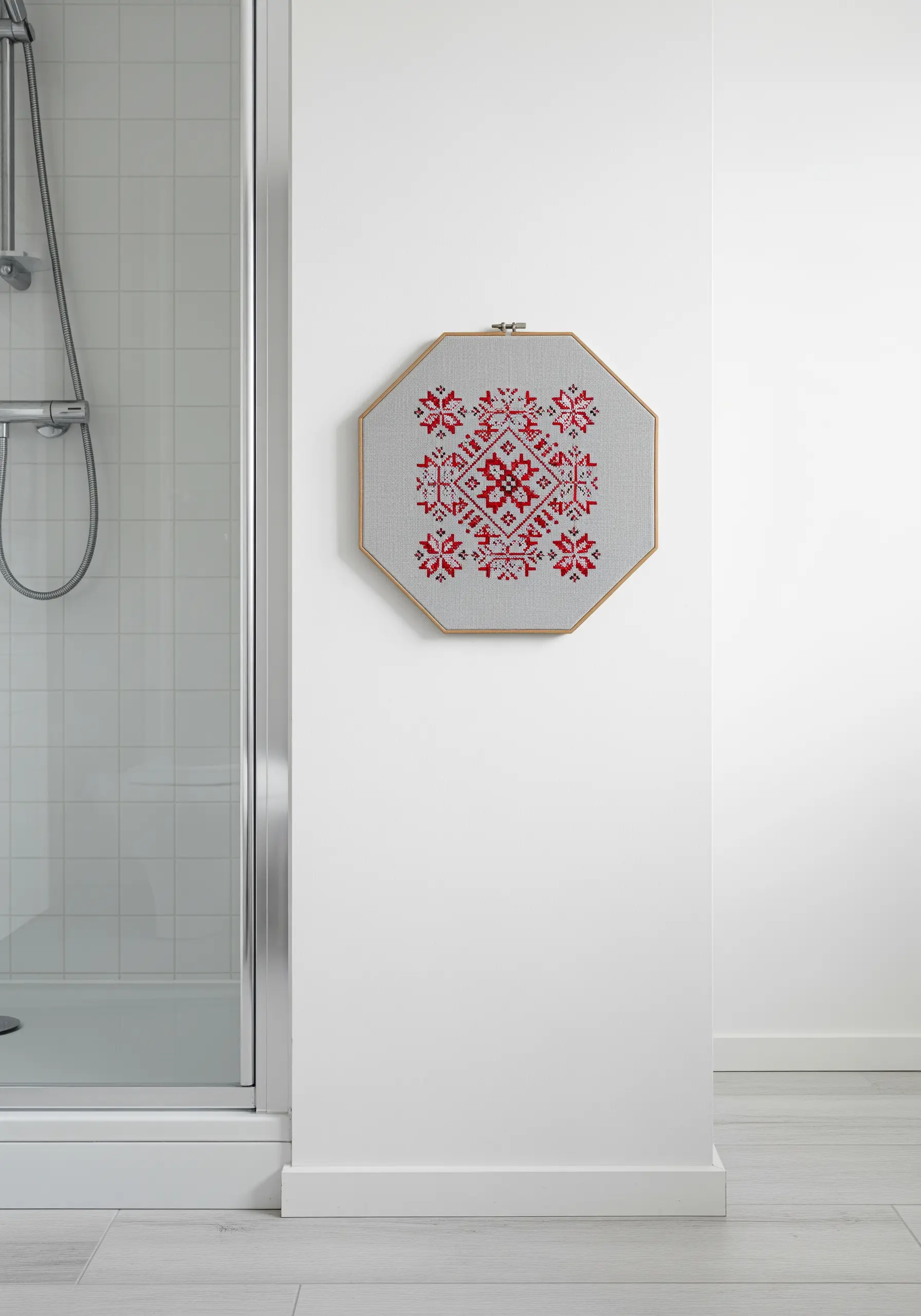 A red geometric cross-stitch pattern mounted in an octagonal hoop.