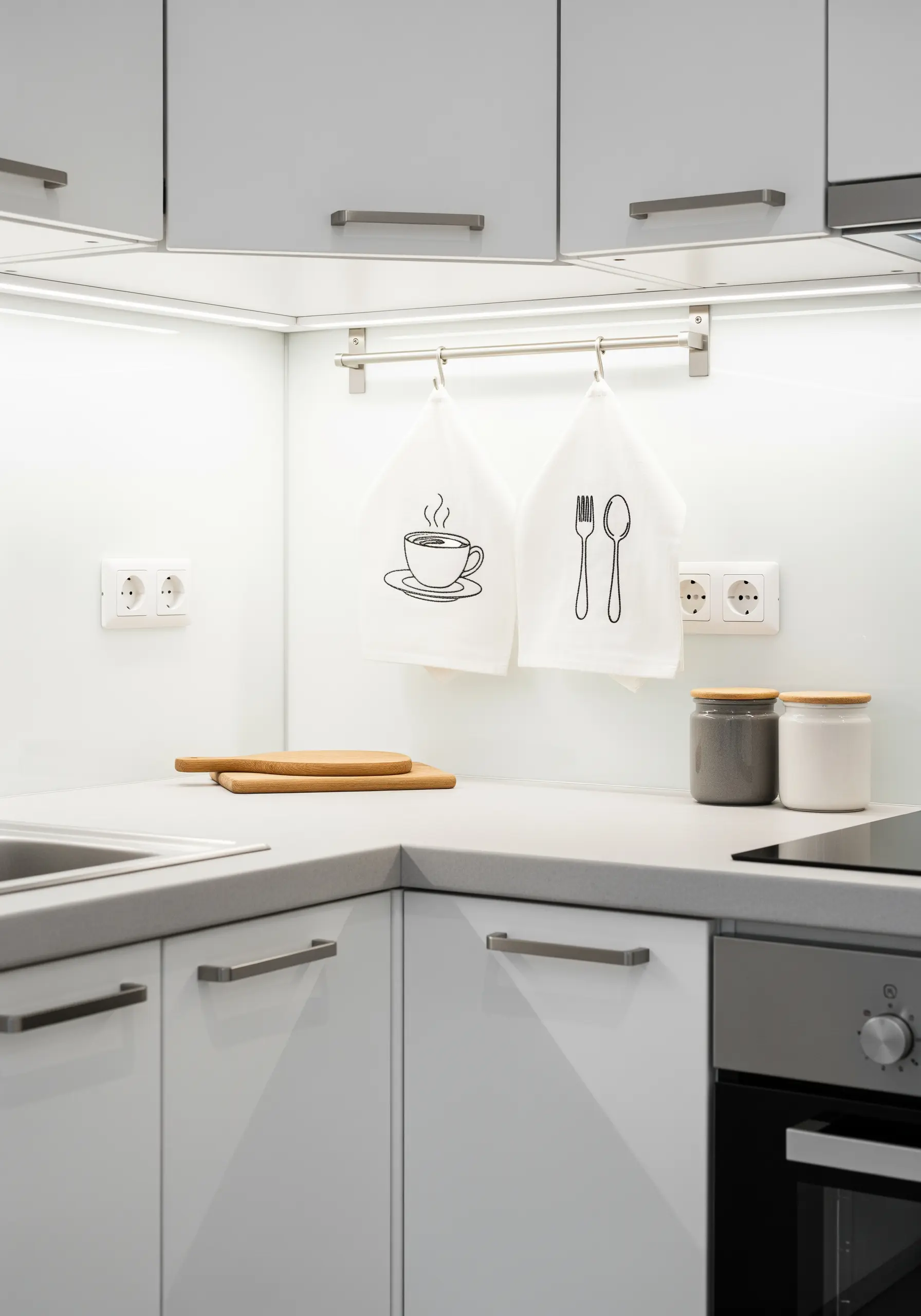 White kitchen towels with simple black line art embroidery of a coffee cup and utensils.
