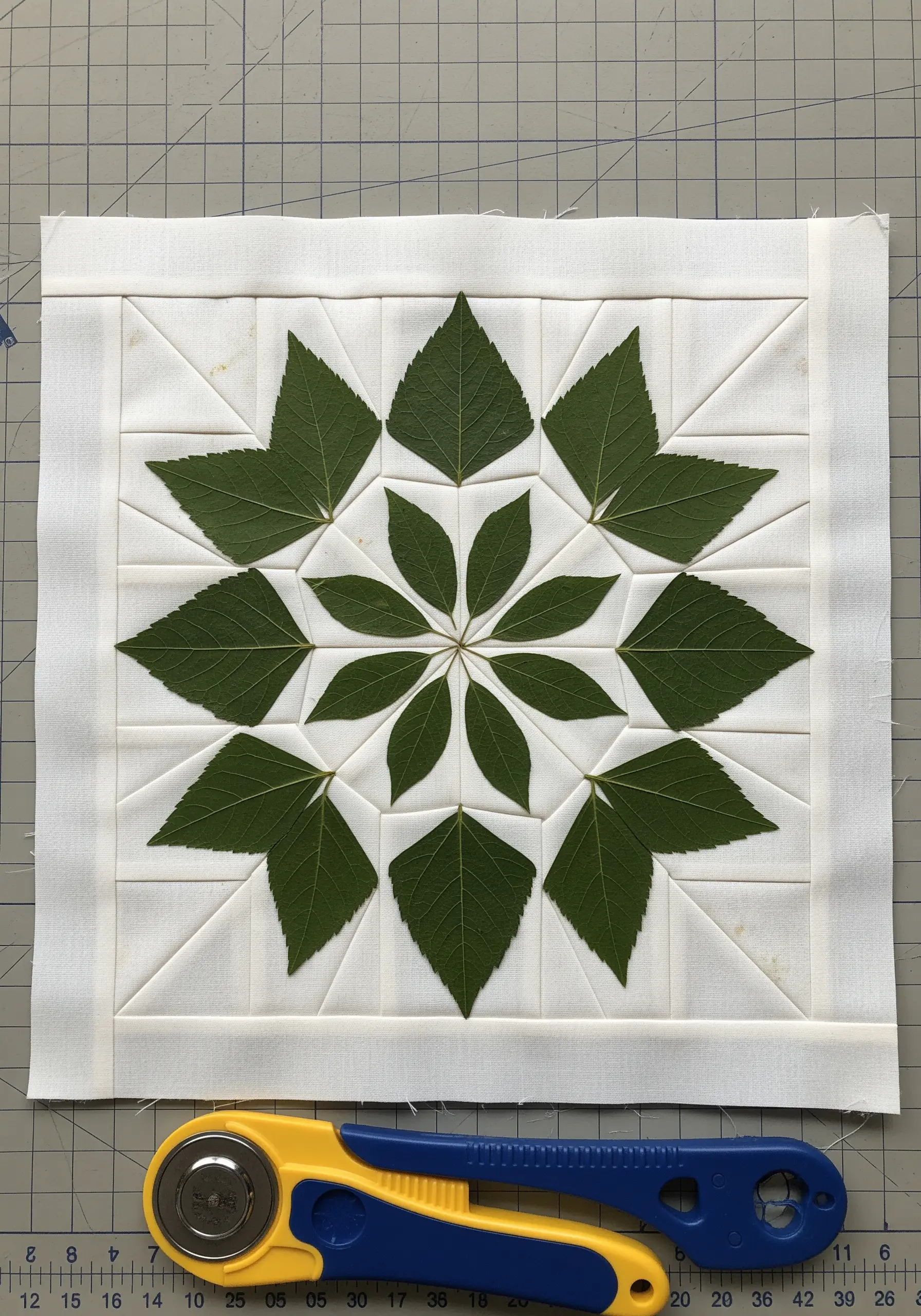 A quilted block with a star pattern made from carefully arranged pressed green leaves.