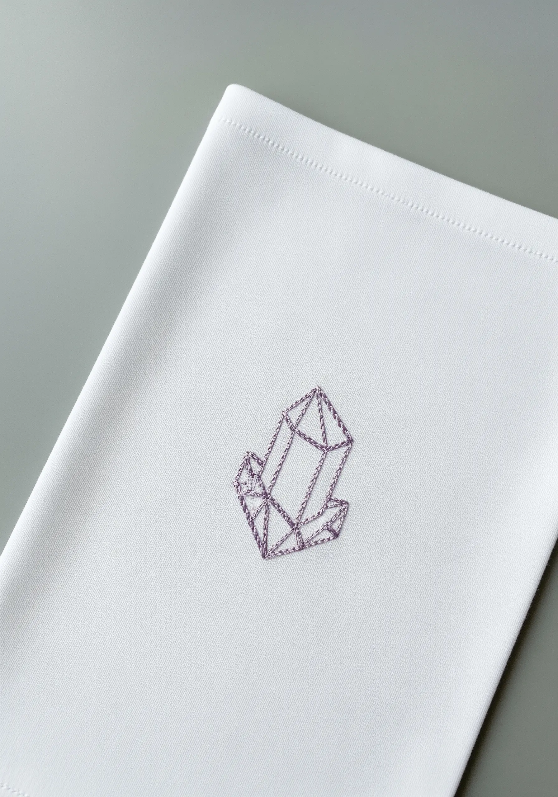 A geometric crystal cluster embroidered in purple on a white handkerchief.
