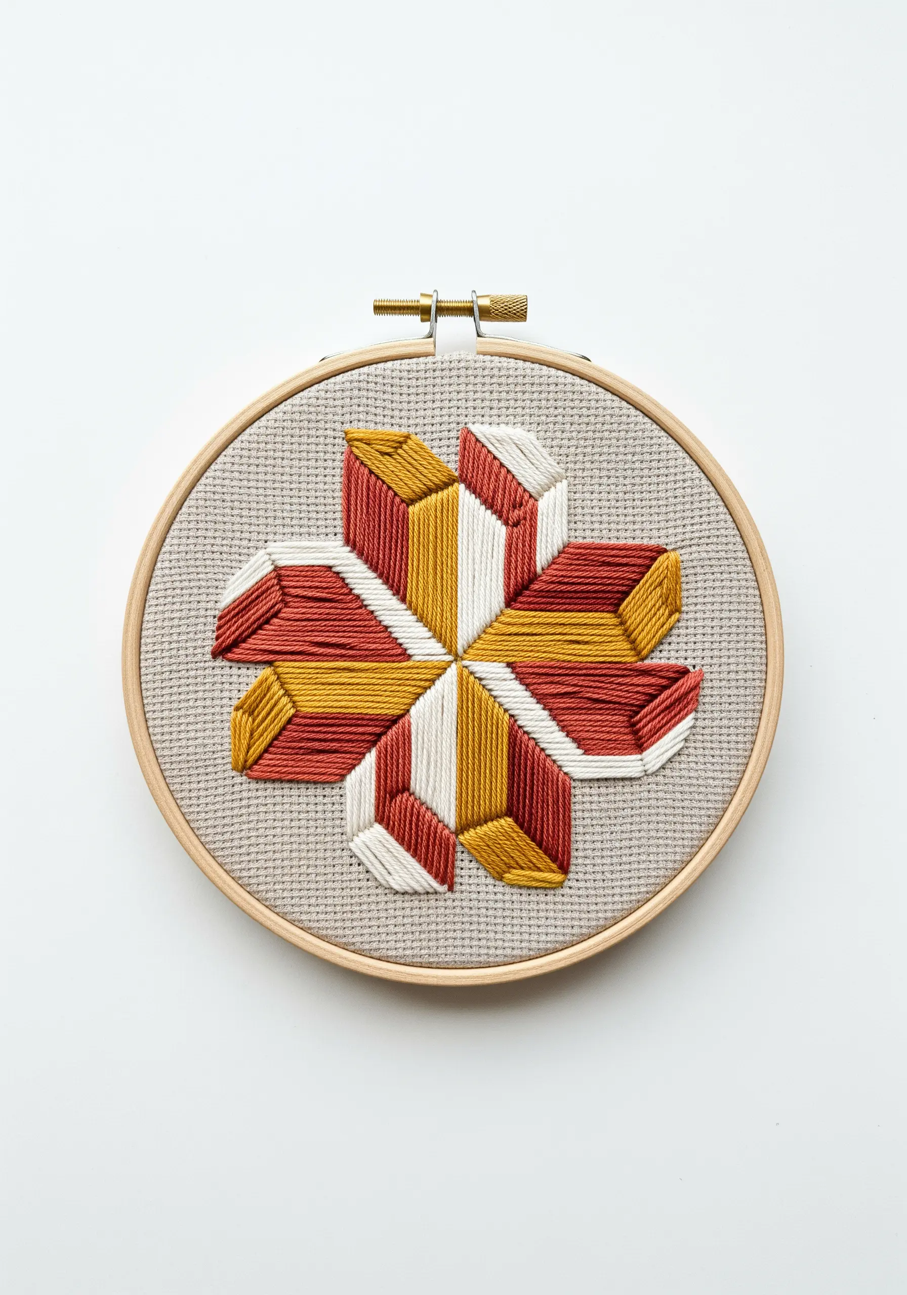 A geometric star-shaped flower embroidered with blocks of red, yellow, and white satin stitch.
