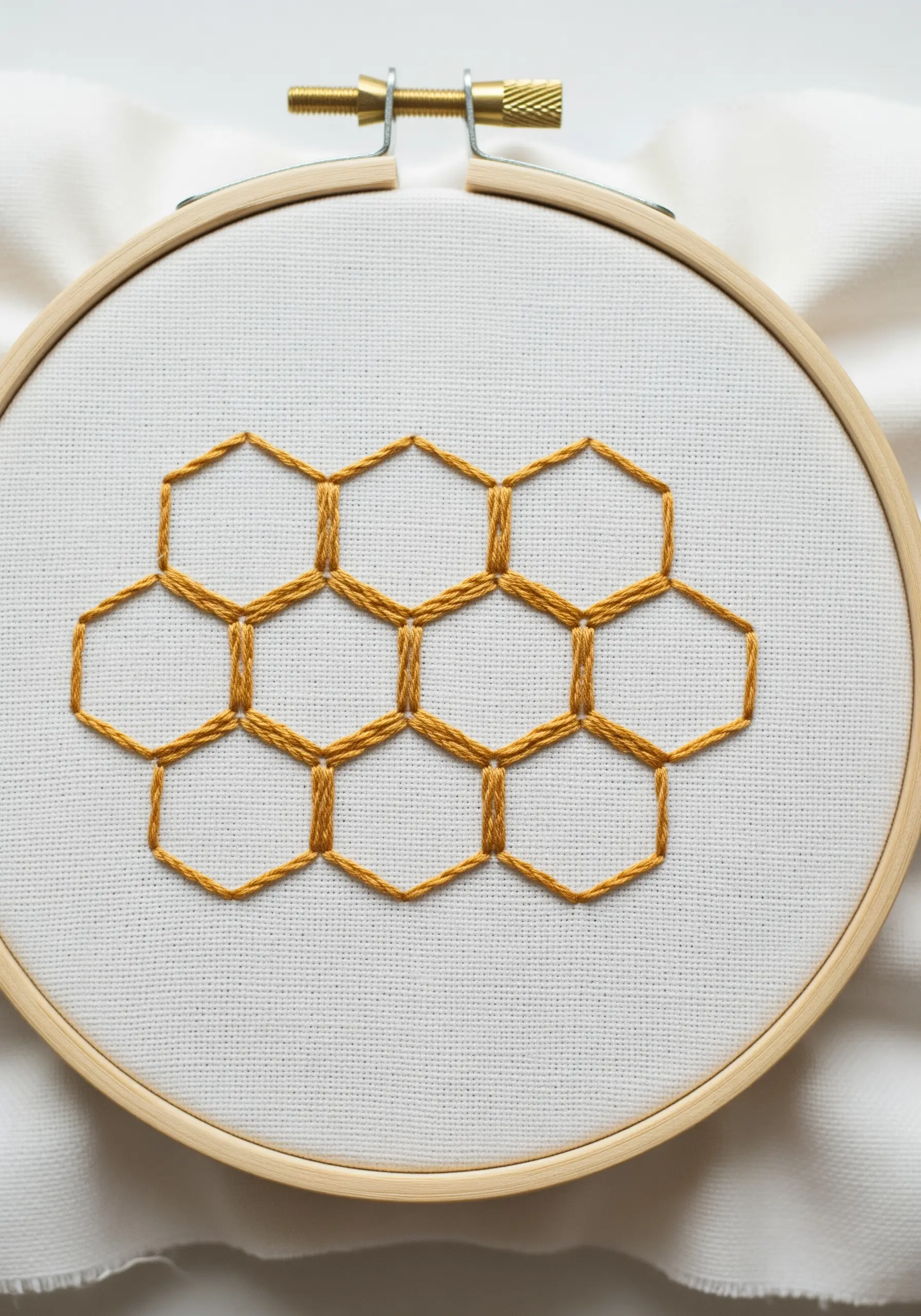 A geometric honeycomb pattern embroidered in golden-yellow thread.
