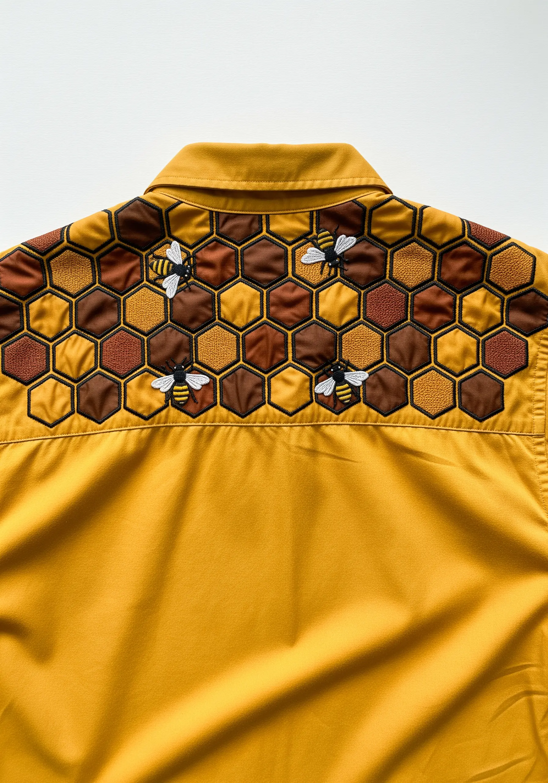 A honeycomb pattern with four bees embroidered on the yoke of a golden yellow shirt.