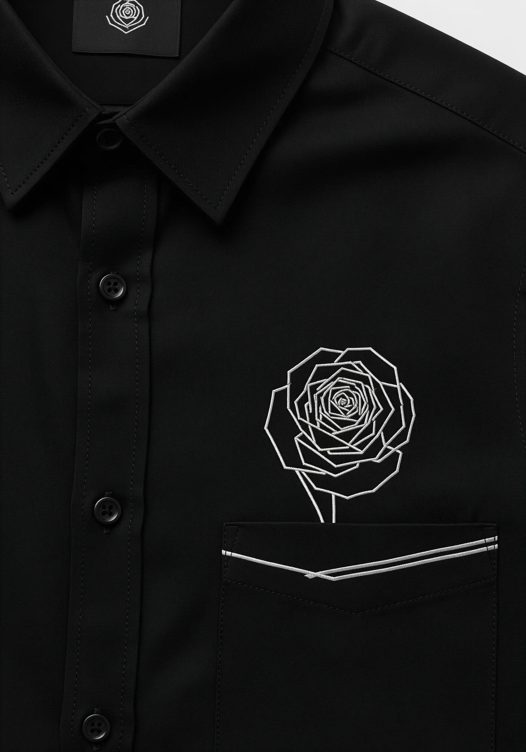 A modern, geometric rose in white line art embroidered on a black shirt.