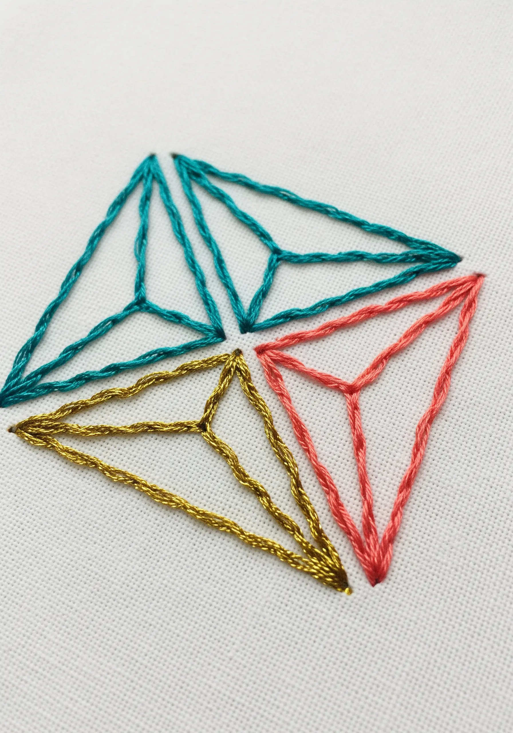Geometric triangle prisms embroidered with metallic and colored threads