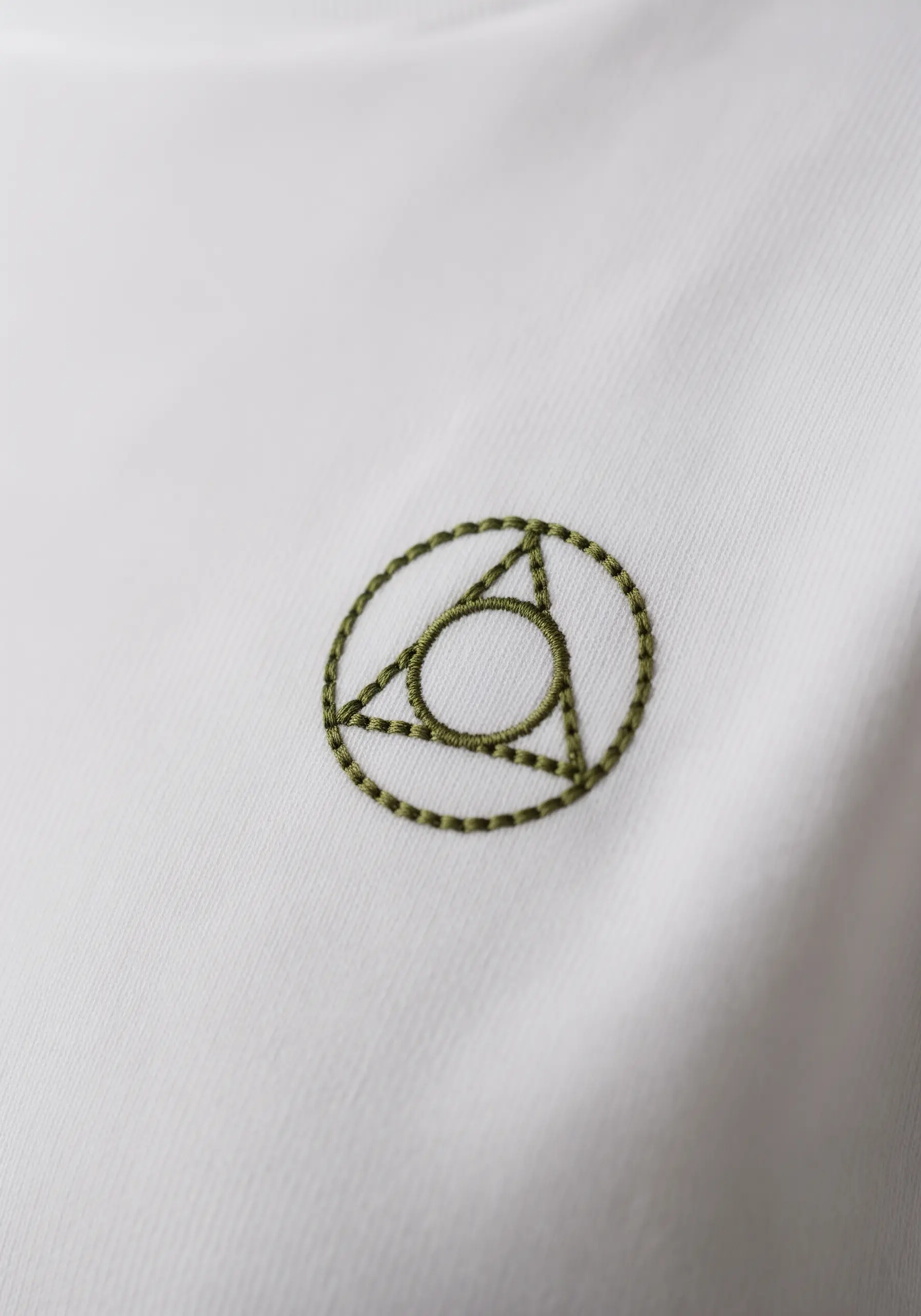 A geometric symbol with a triangle in a circle, stitched in olive green.