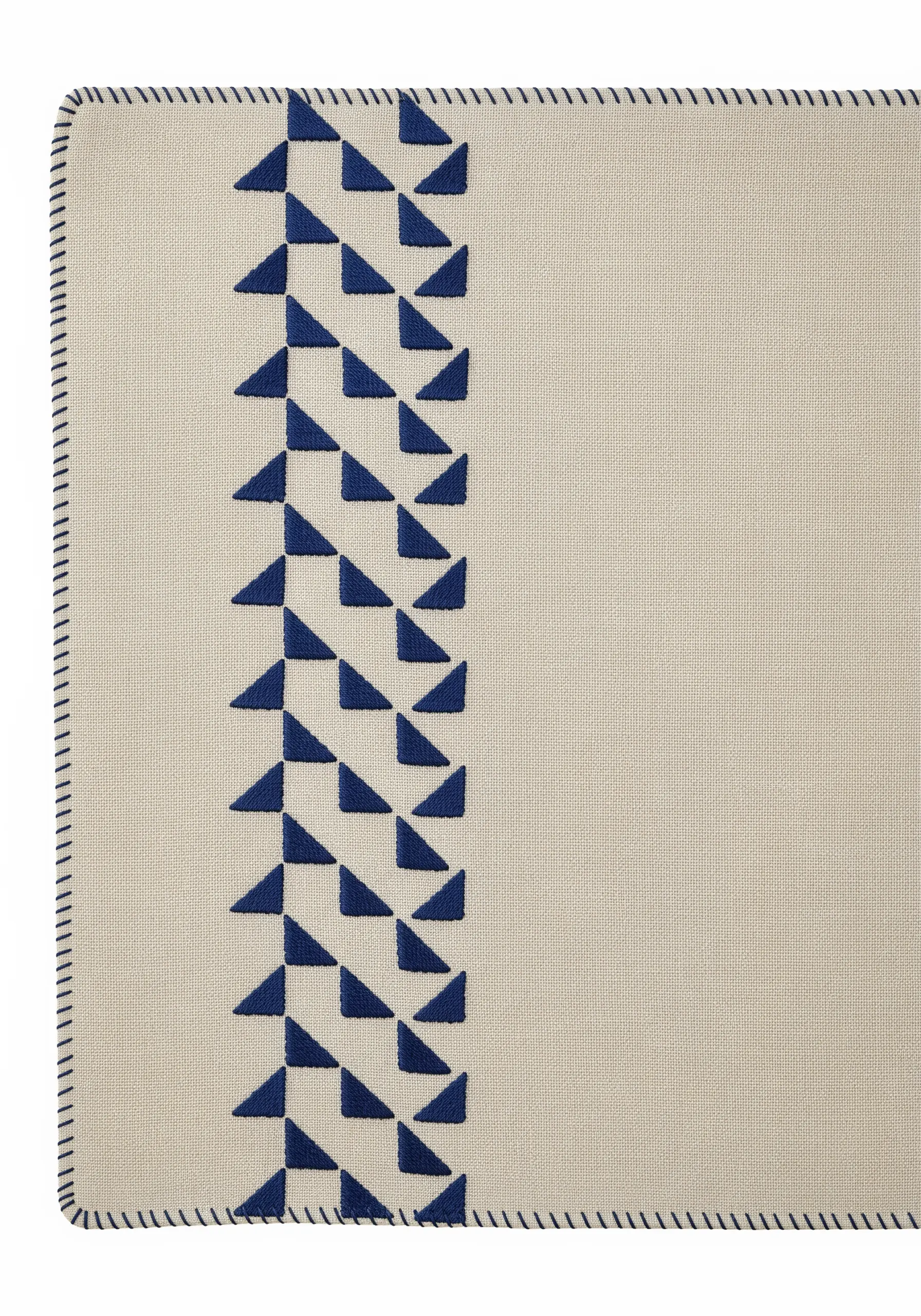 A placemat border of geometric triangles filled with blue satin stitch.