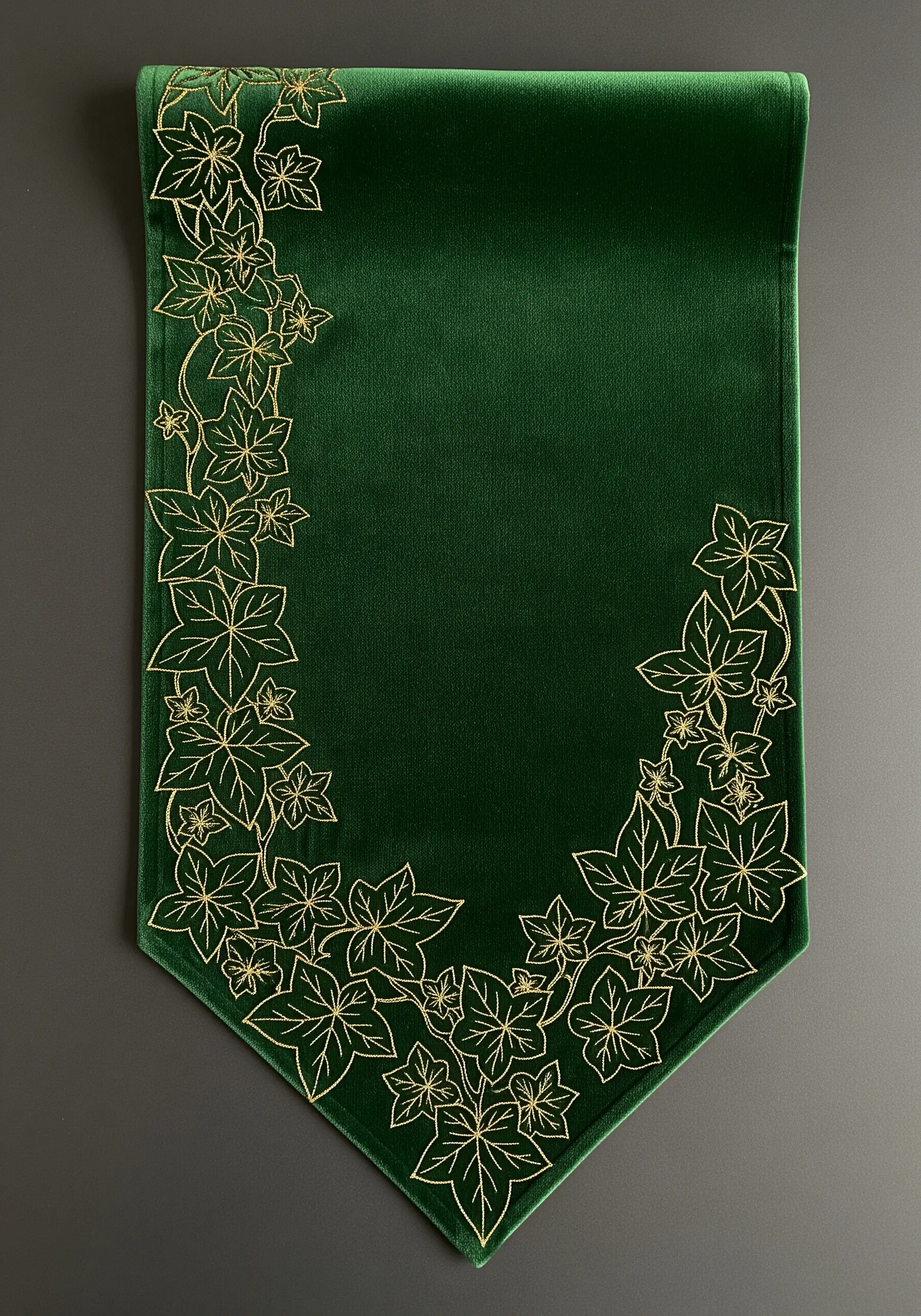 A luxurious dark green velvet table runner with an ornate border of ivy embroidered in gold thread.